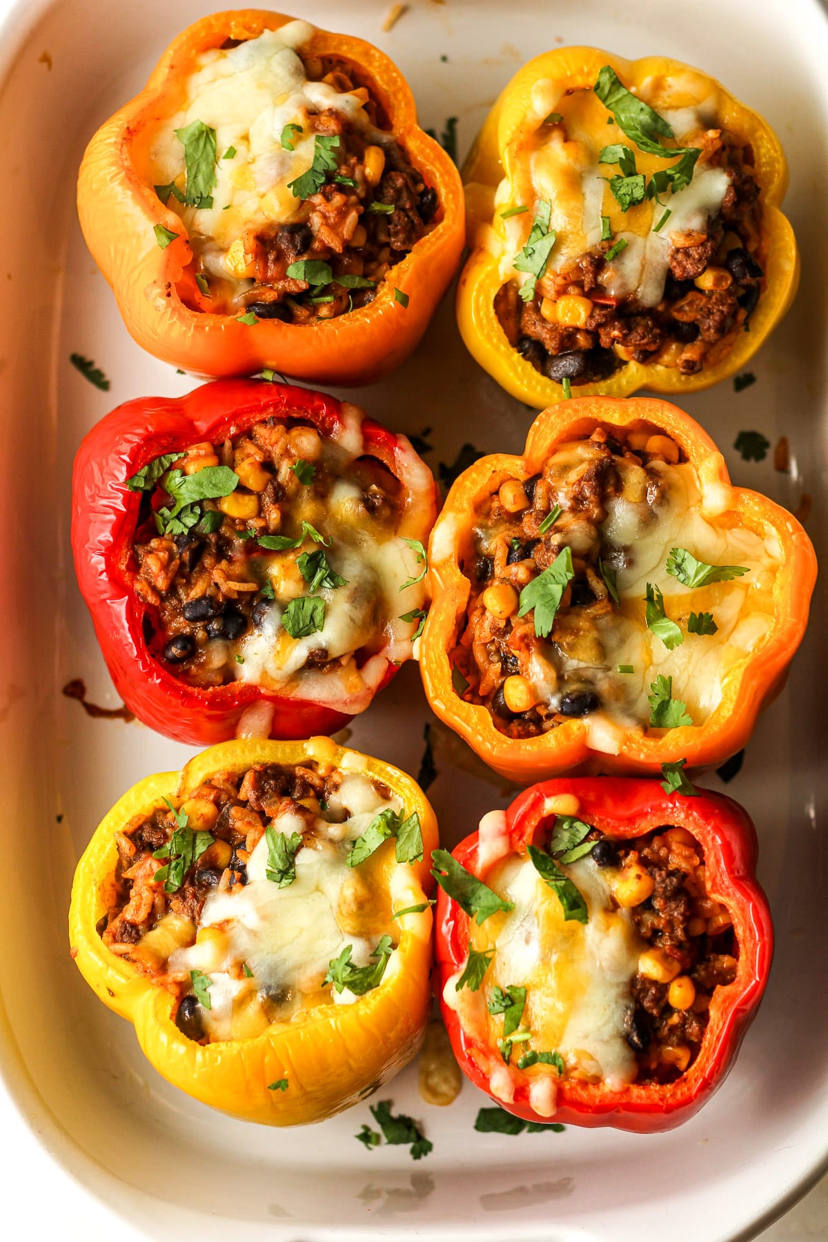 A casserole with six stuffed bell peppers after baking.