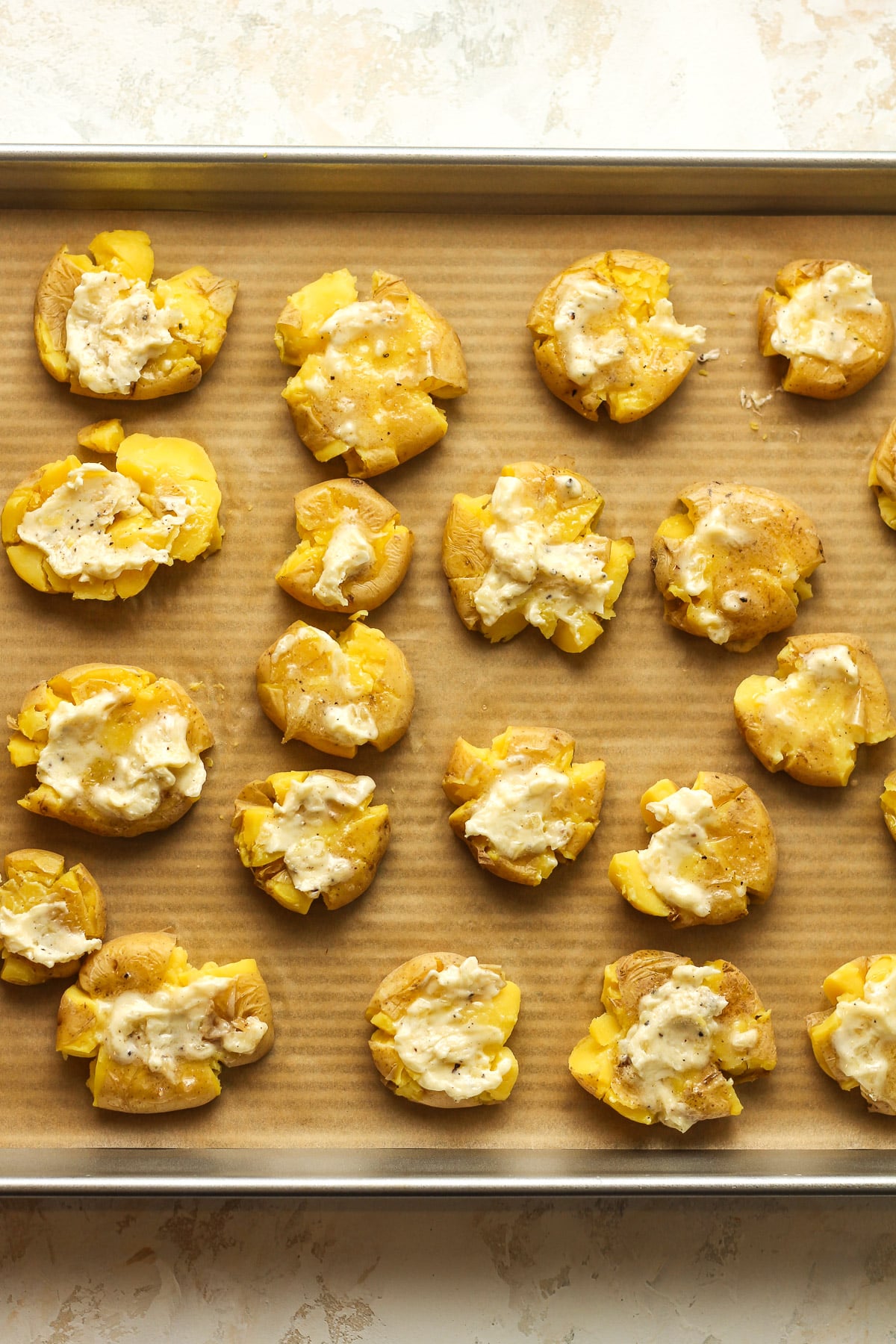 A tray of the smashed potatoes with the garlic butter on top.