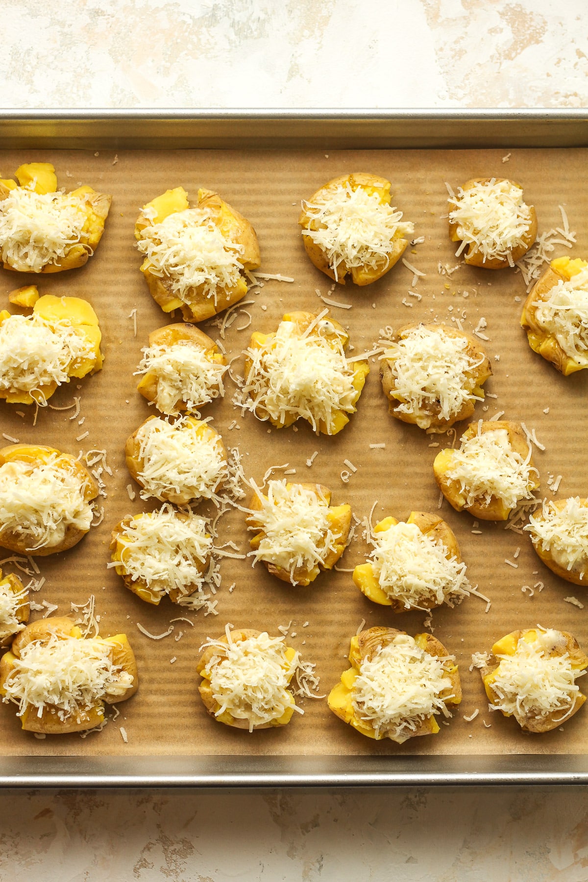 A tray of the smashed potatoes with the garlic parmesan mixture on top.