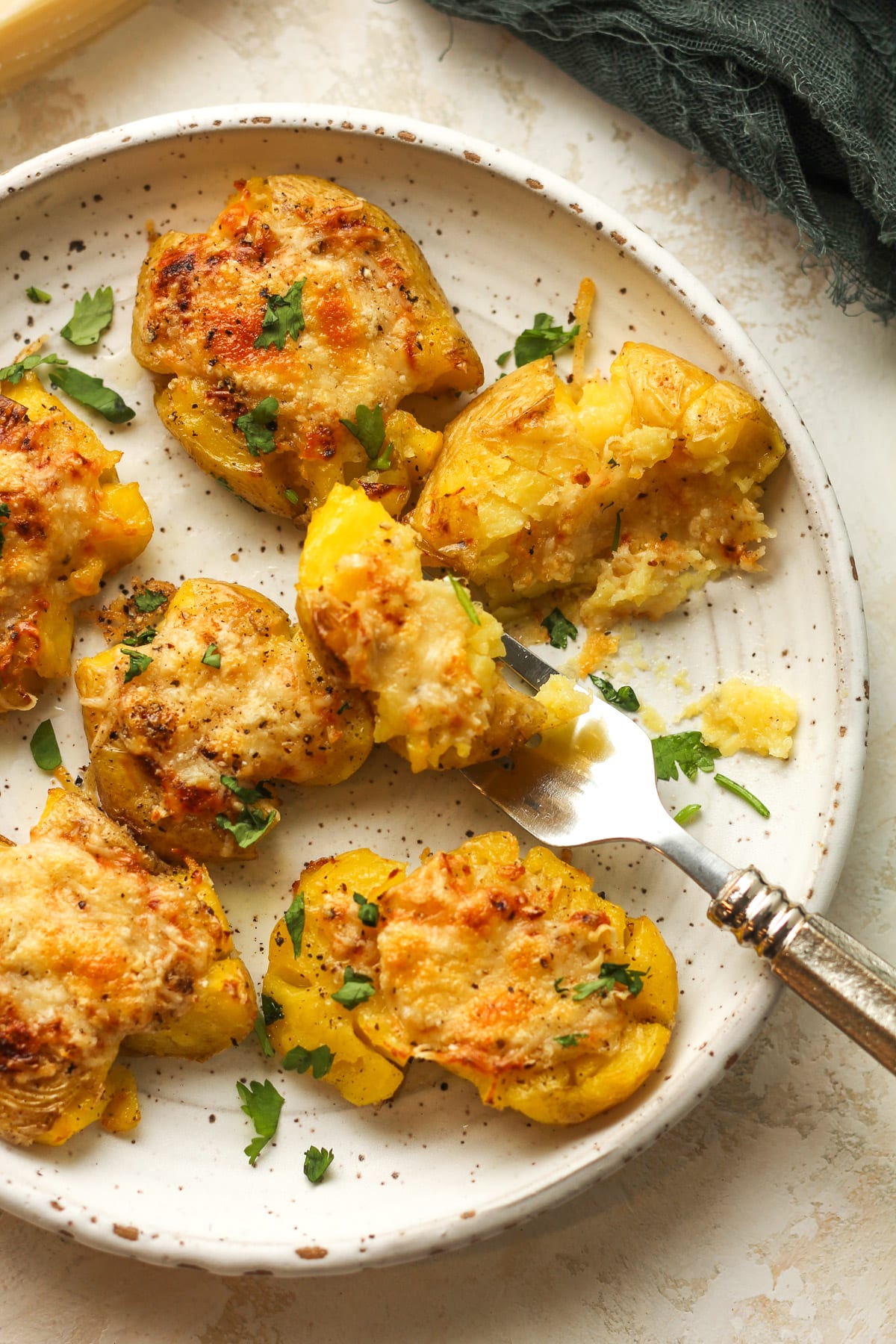 A plate of smashed potatoes with a forkful.