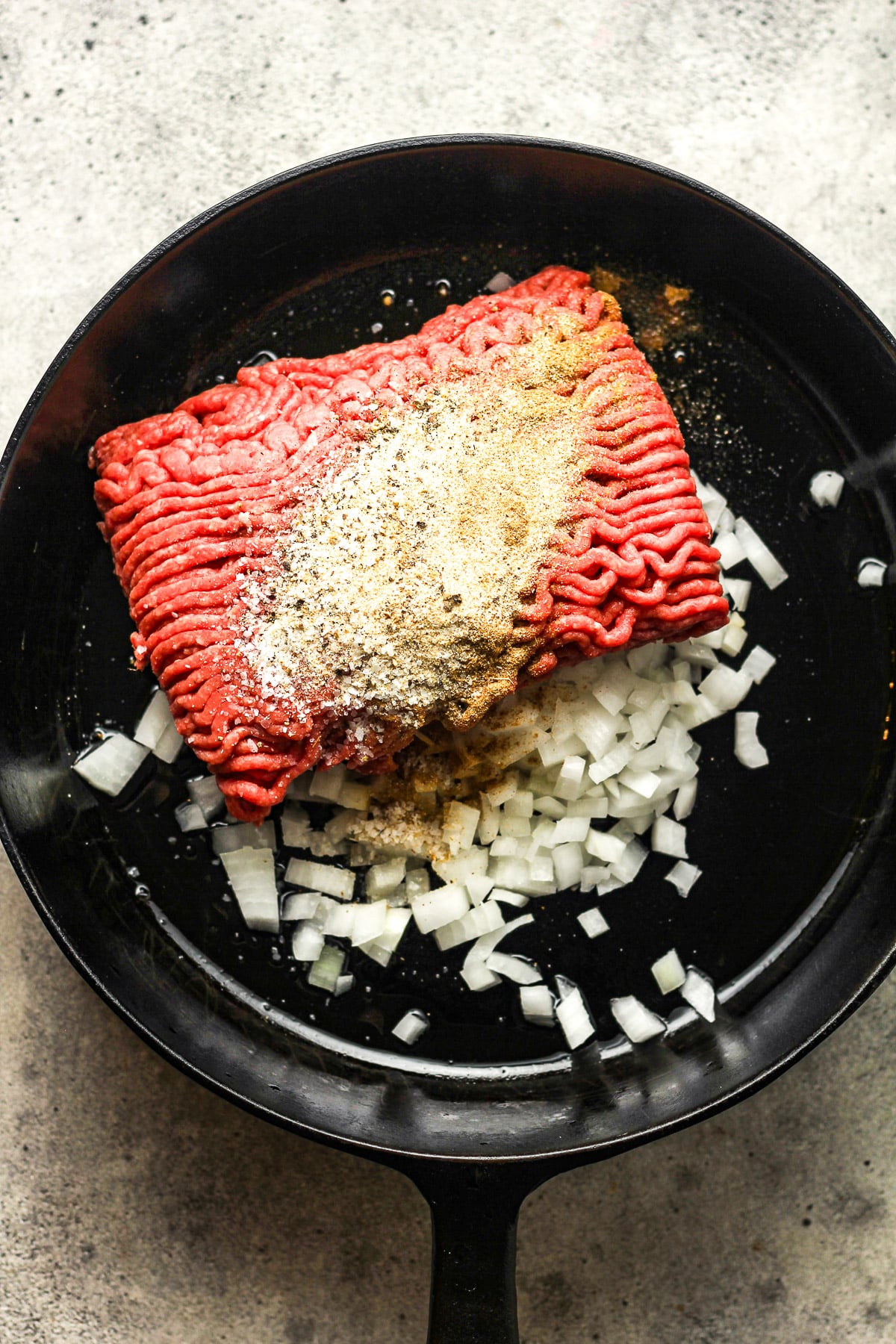 A skillet of onions, ground beef and seasonings.