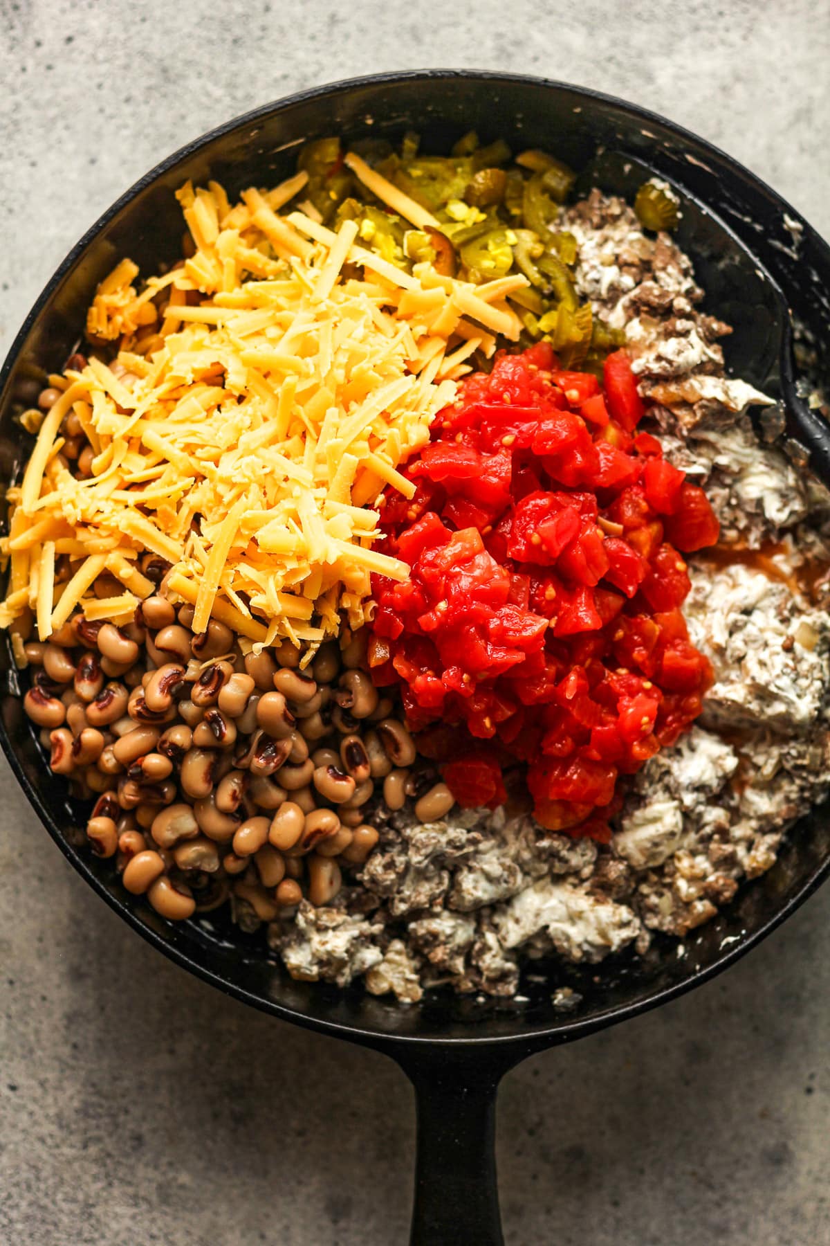 A skillet with the creamy beef mixture and remaining ingredients on top.