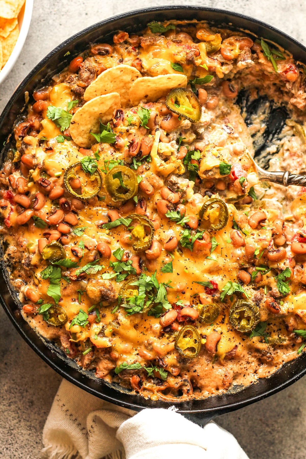 The skillet with a spoon inside scooping some dip out.