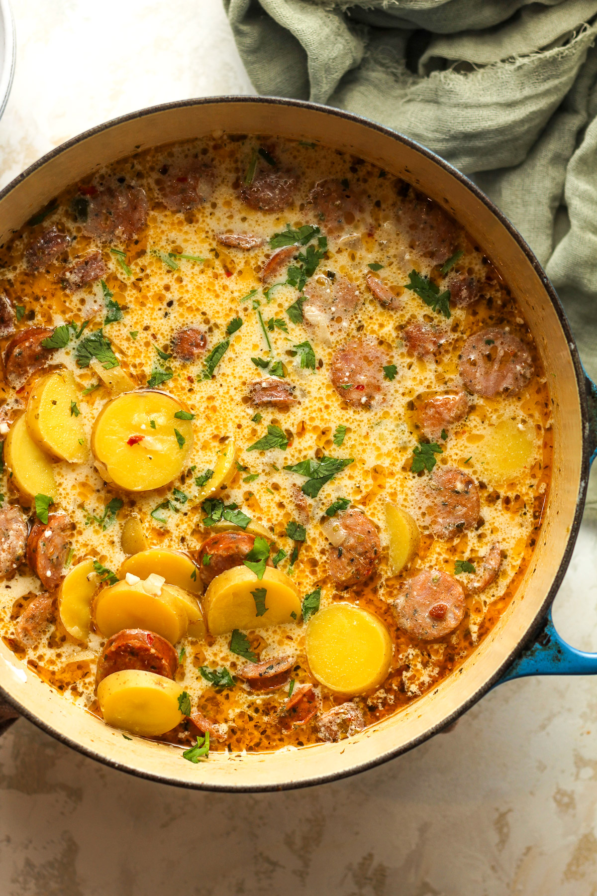 A large pot of kielbasa potato soup with a green napkin.