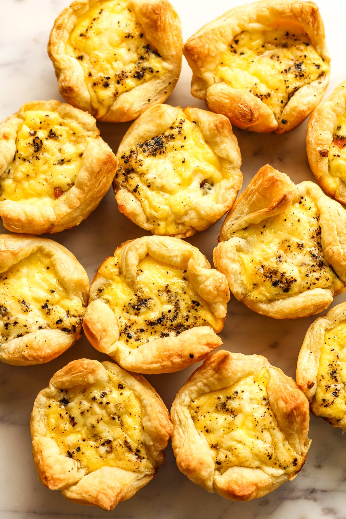 Overhead view of several mini quiche in puff pastry.