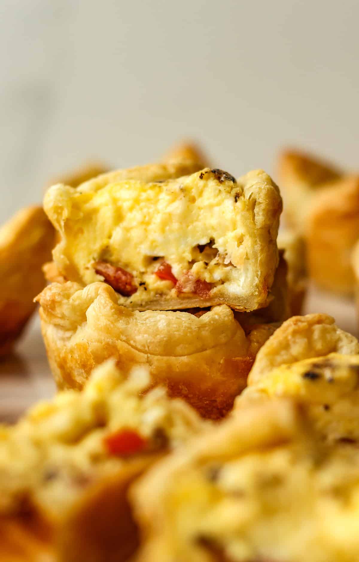 Two stacked mini quiche, one split in half showing the soft interior.