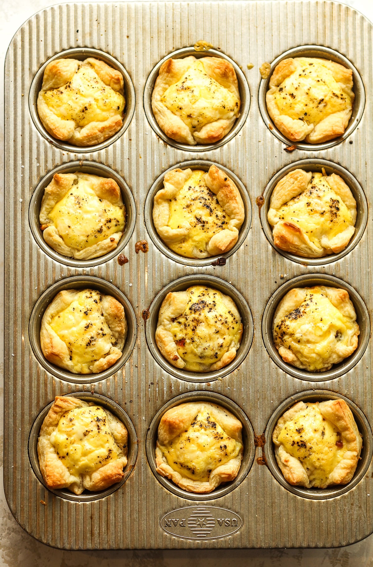 The just baked mini quiche in puff pastry in a muffin tin.