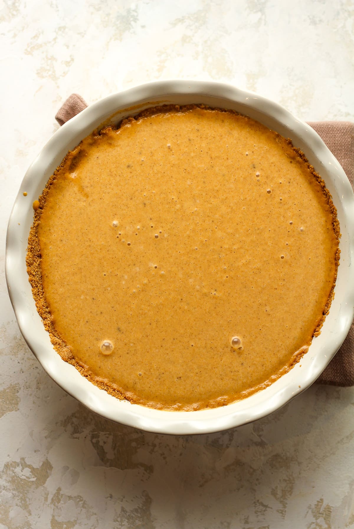 A graham cracker crust with the filling inside ready to bake.