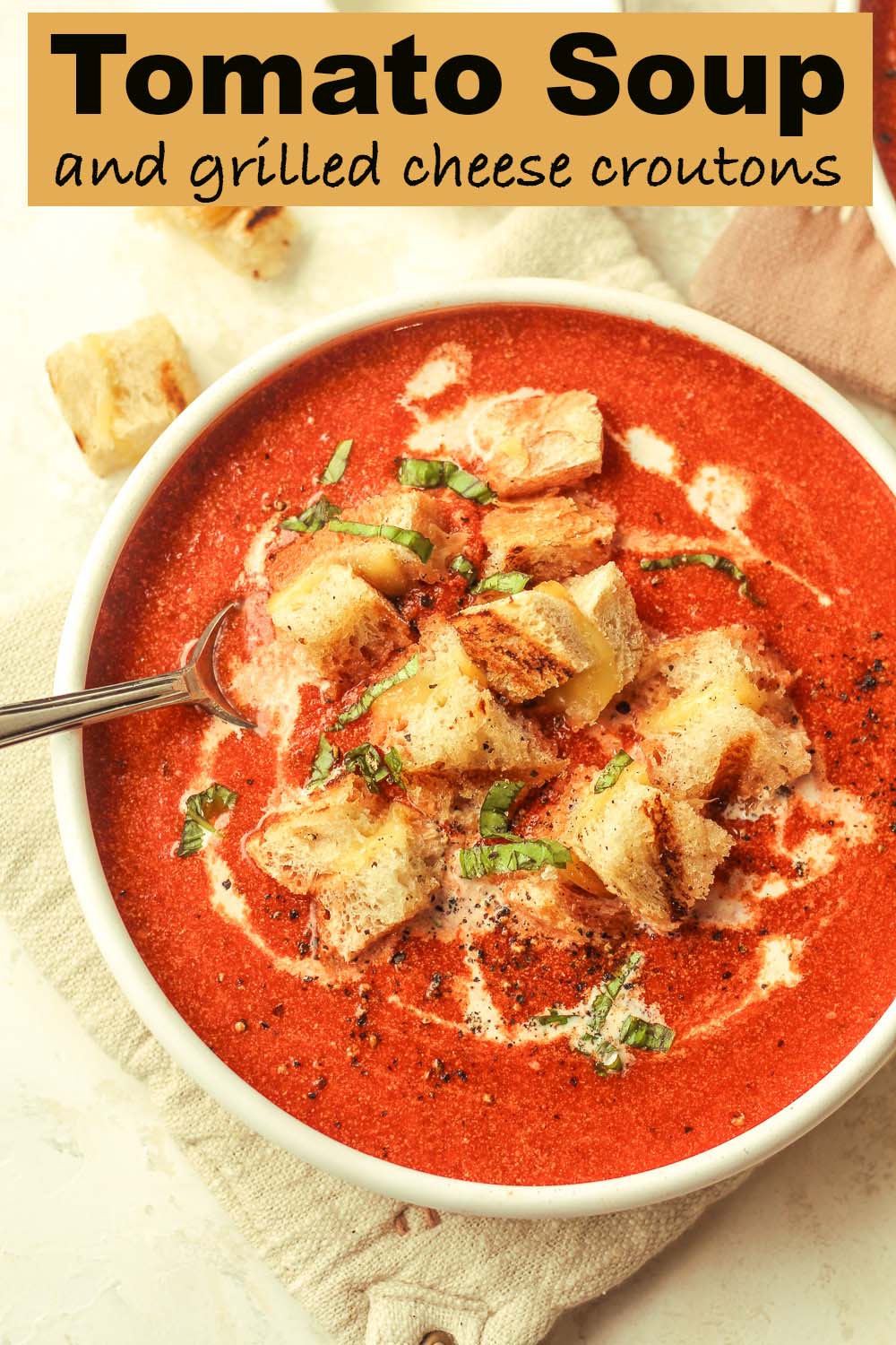 A bowl of tomato soup and grilled cheese croutons.