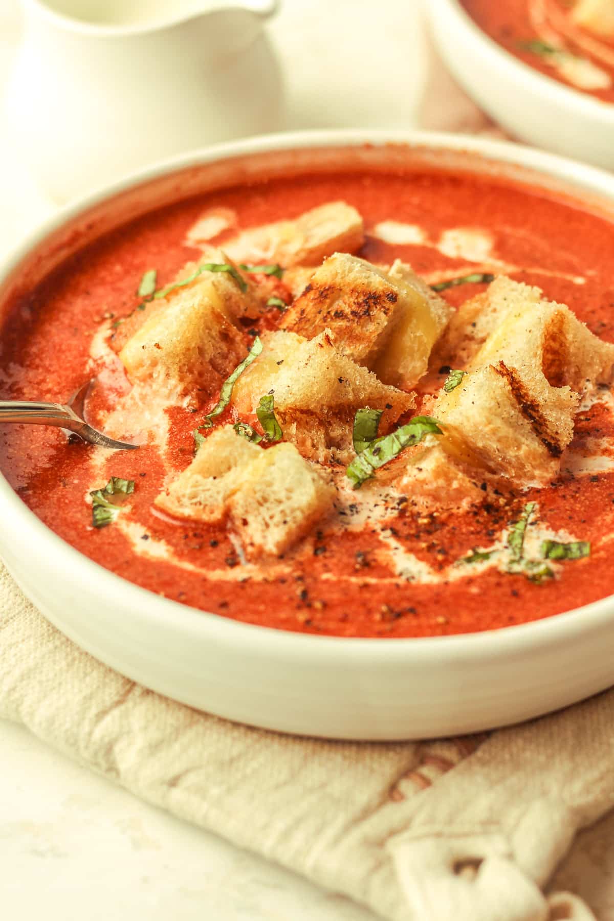 Side view of a bowl of tomato soup and croutons.