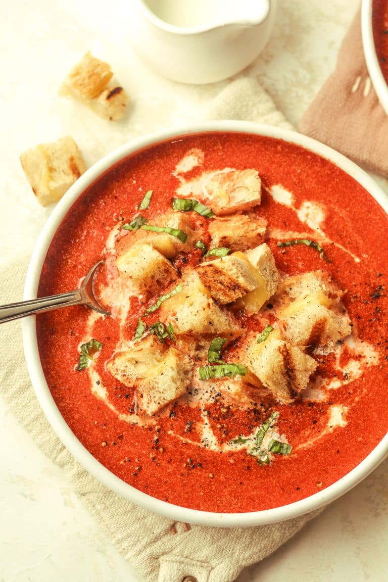 A shallow bowl of tomato soup with grilled cheese croutons.