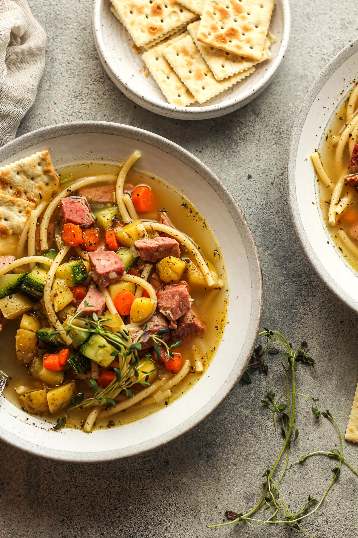 Overhead view of two bowls of ham and veggie soup with thyme.