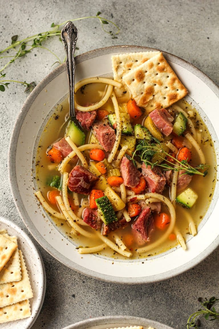 A shallow bowl of veggie soup with leftover ham and crackers.