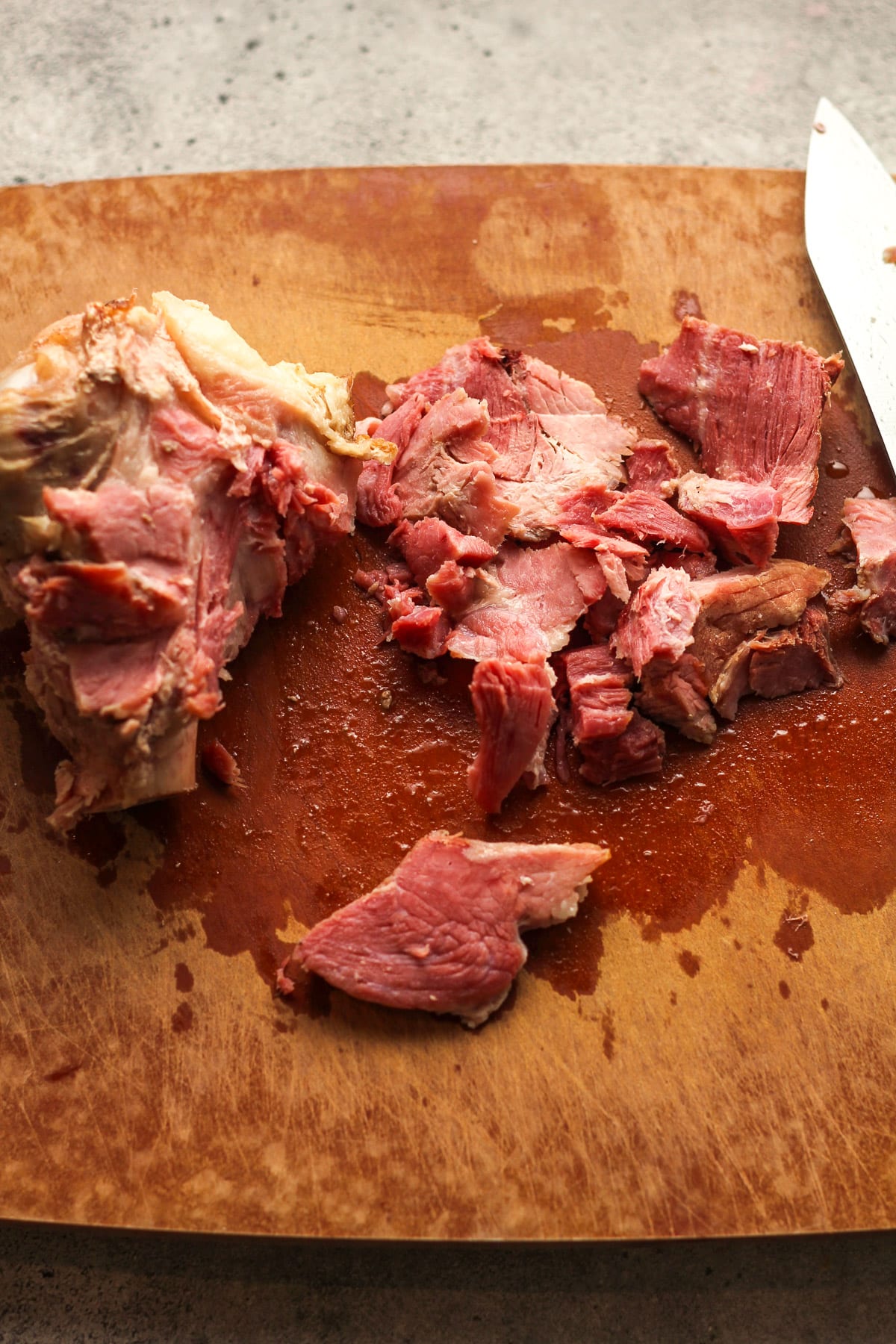 A cutting board with the ham bone plus ham chunks.