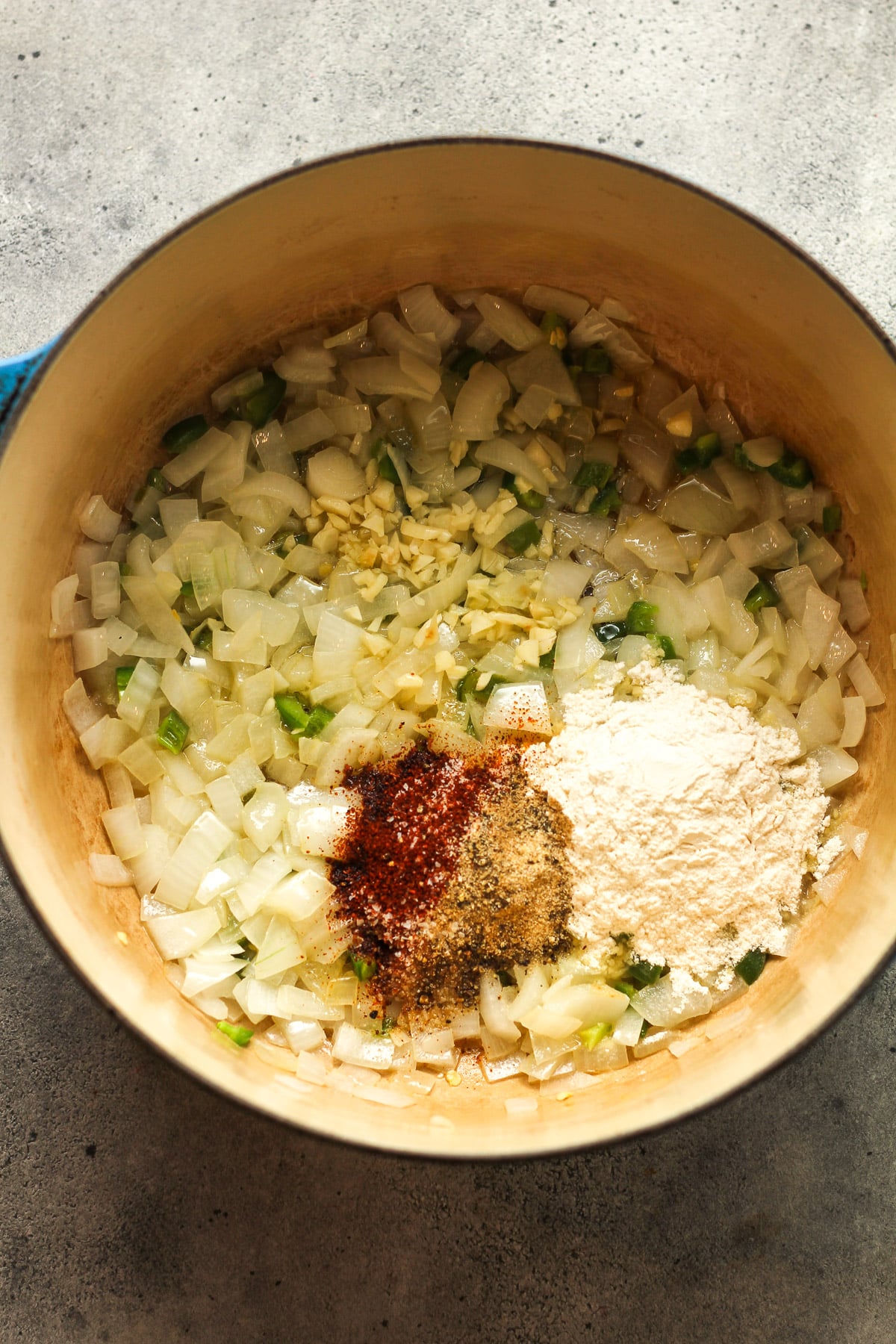 A stock pot of the sautéed veggies plus flour and seasonings on top.