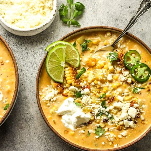 Two bowls of Mexican Street Corn chowder with lime slices.
