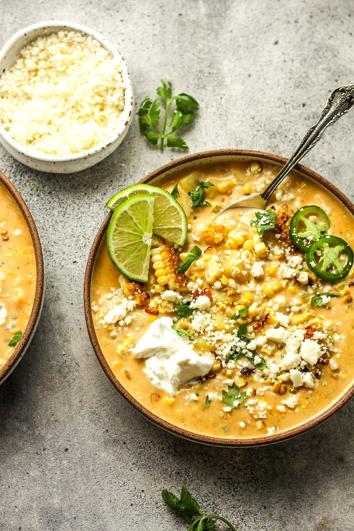 Two bowls of Mexican Street Corn chowder with lime slices.