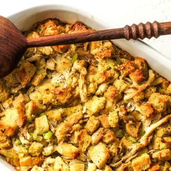 Closeup on a casserole dish of Thanksgiving stuffing with a wooden spoon.