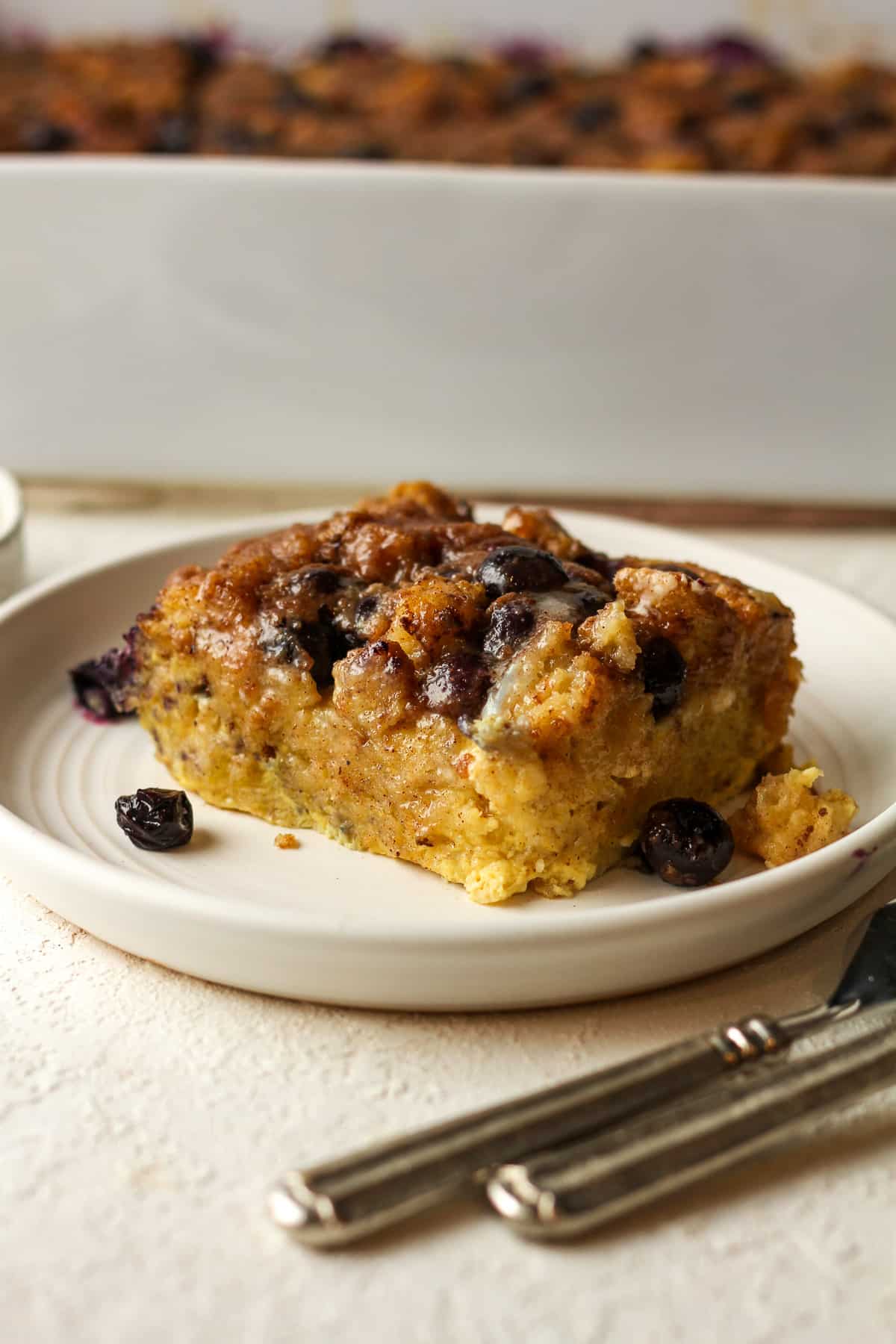 A plate of French toast casserole in front of a casserole.