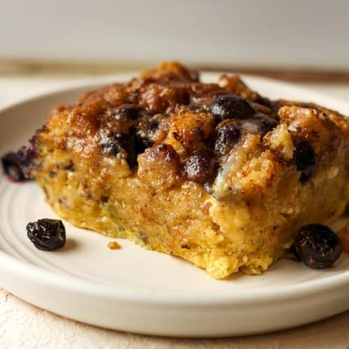 Side view of a plate with a serving of French toast casserole with fresh blueberries.