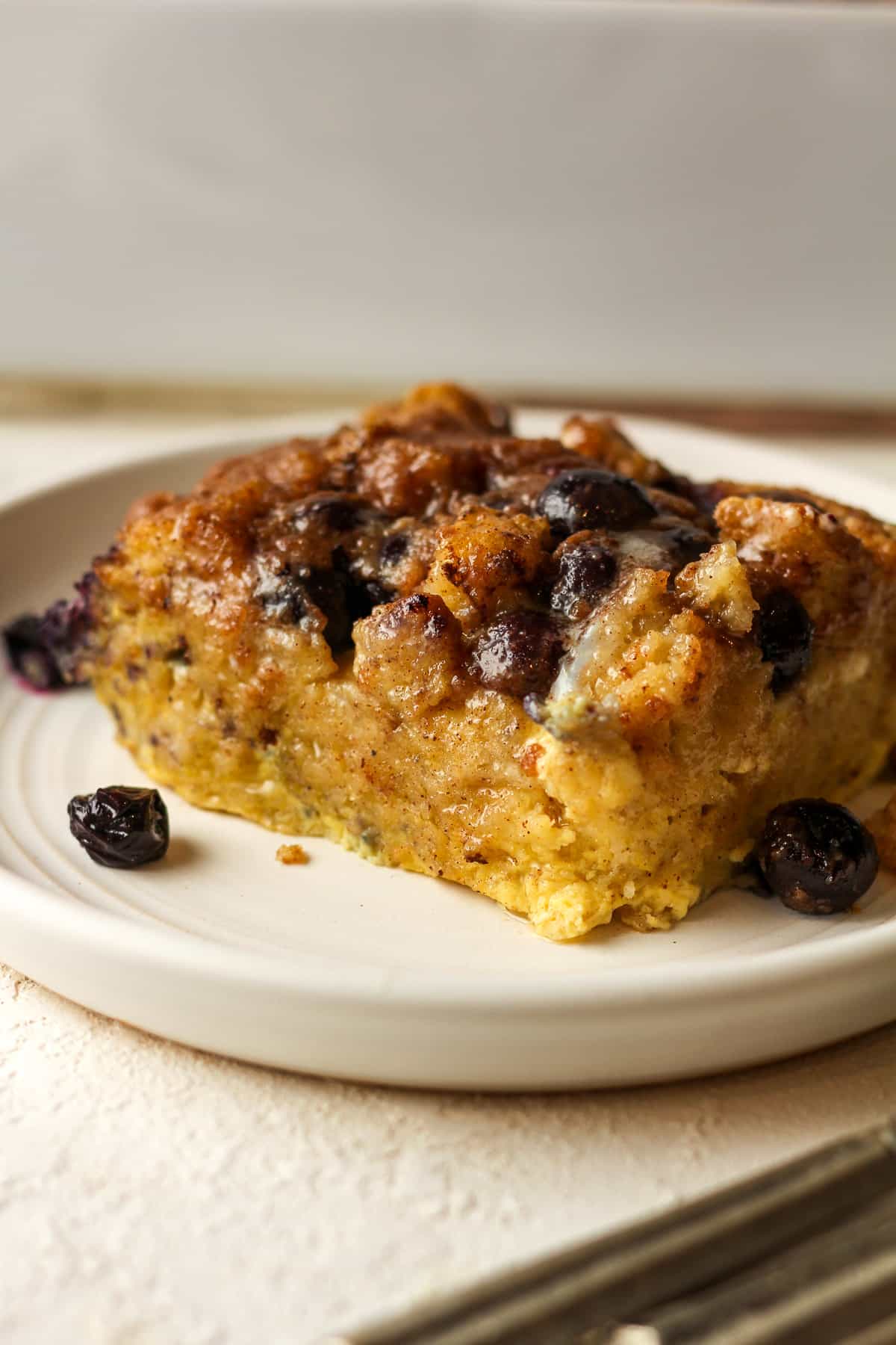 Side view of a plate with a serving of French toast casserole with fresh blueberries.