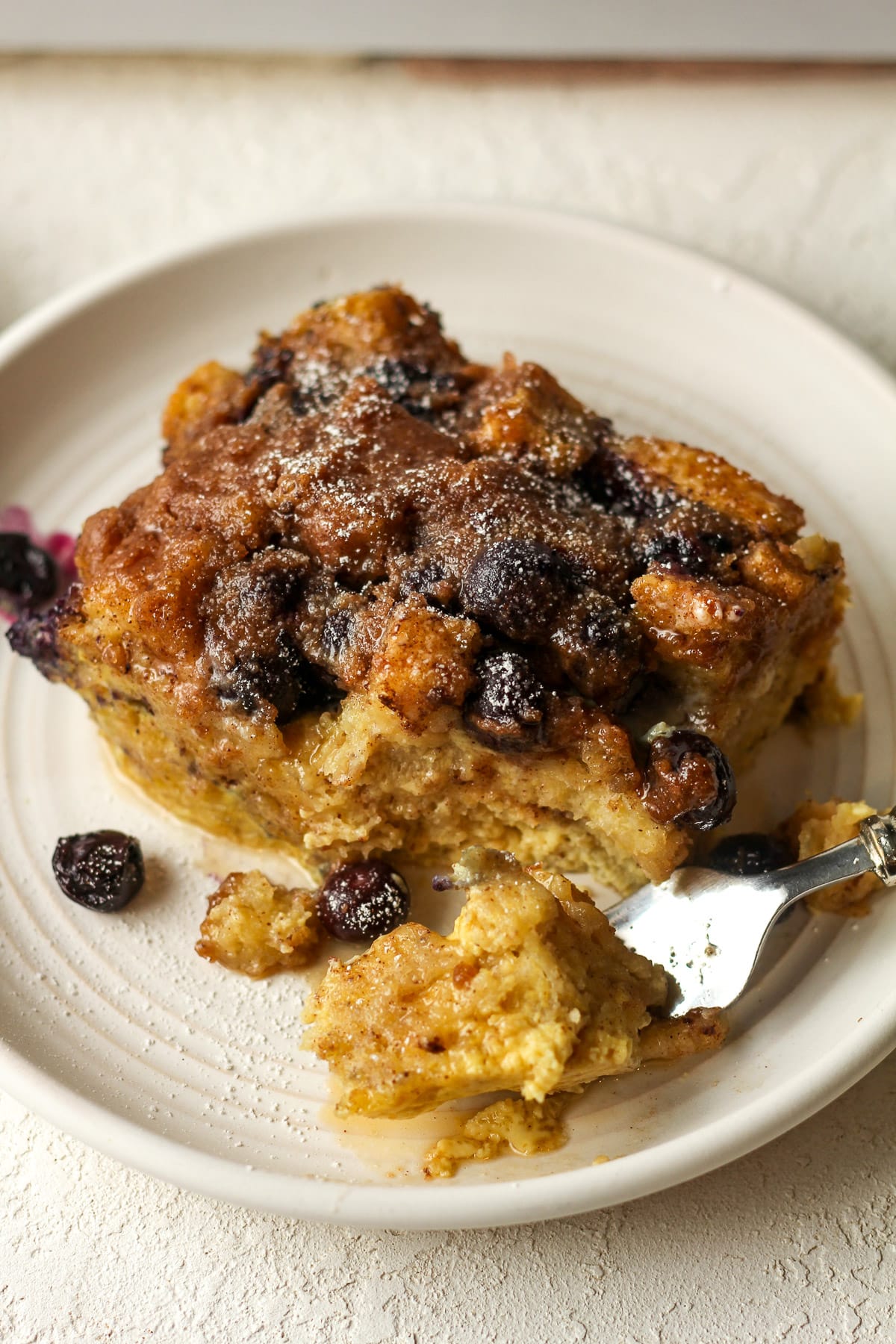 Overhead view of a square of blueberry French toast casserole with a fork.