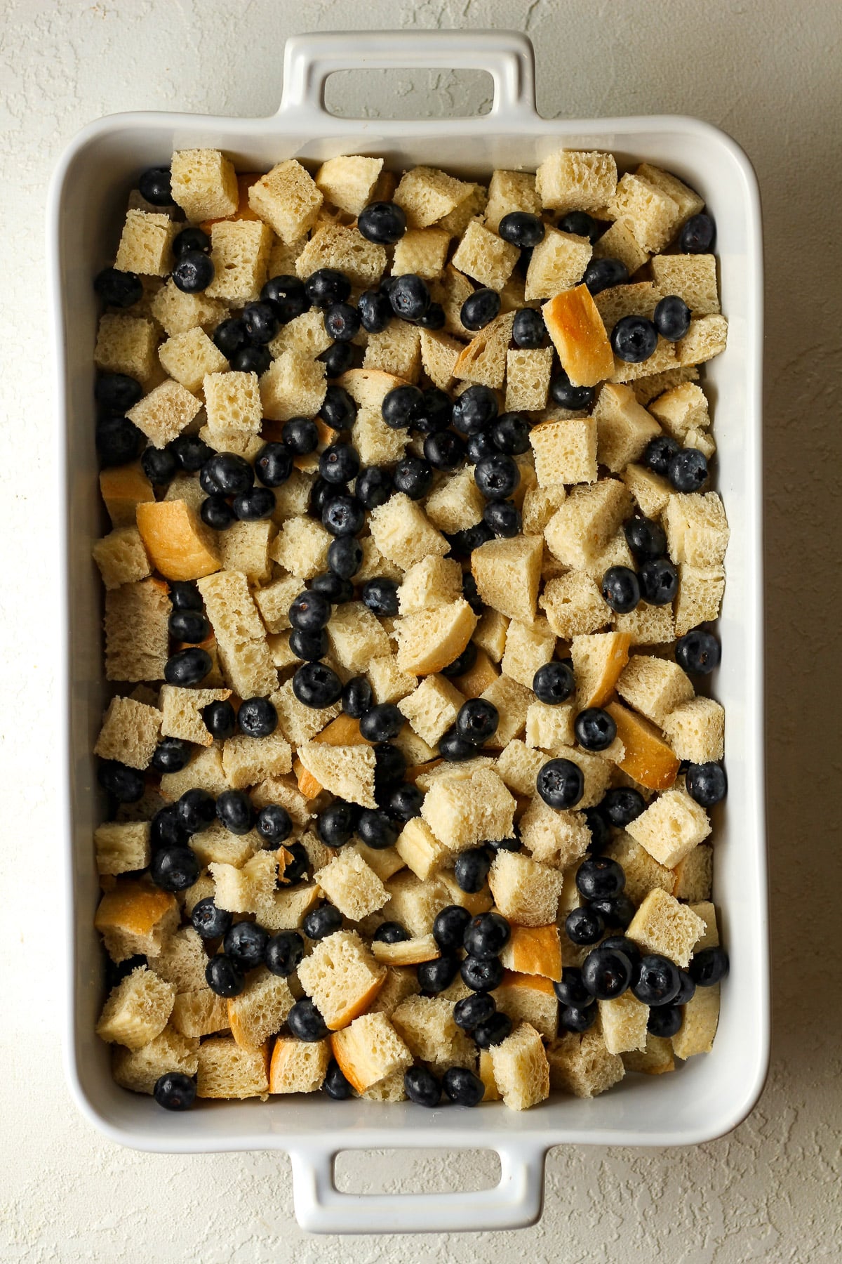 A casserole dish of the cubed bread and fresh blueberries.