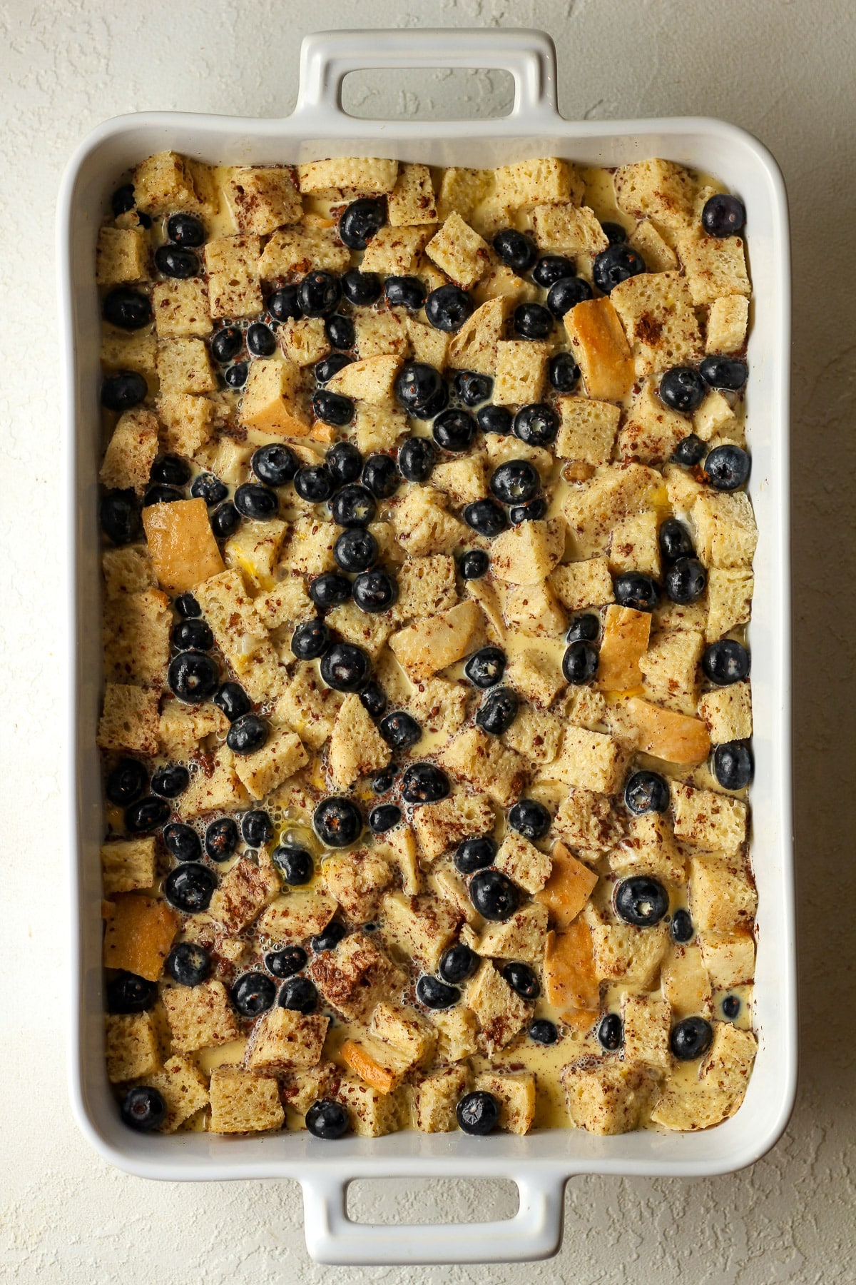 The casserole after adding the egg custard over the cubed bread and blueberries.