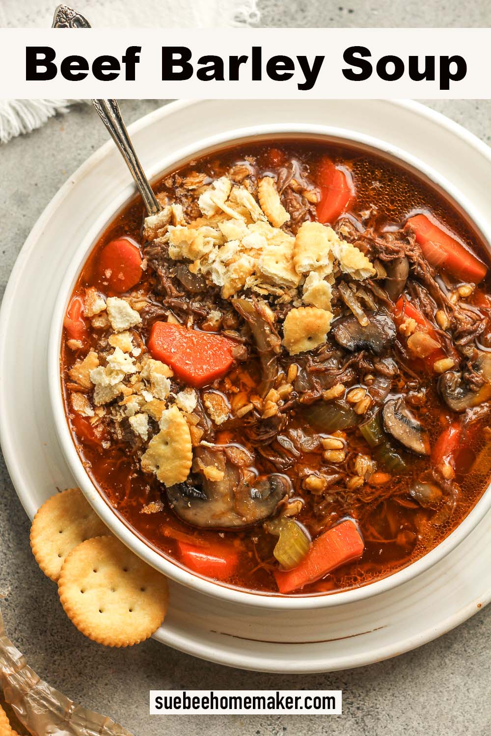 A bowl of beef barley soup with crushed ritz crackers.