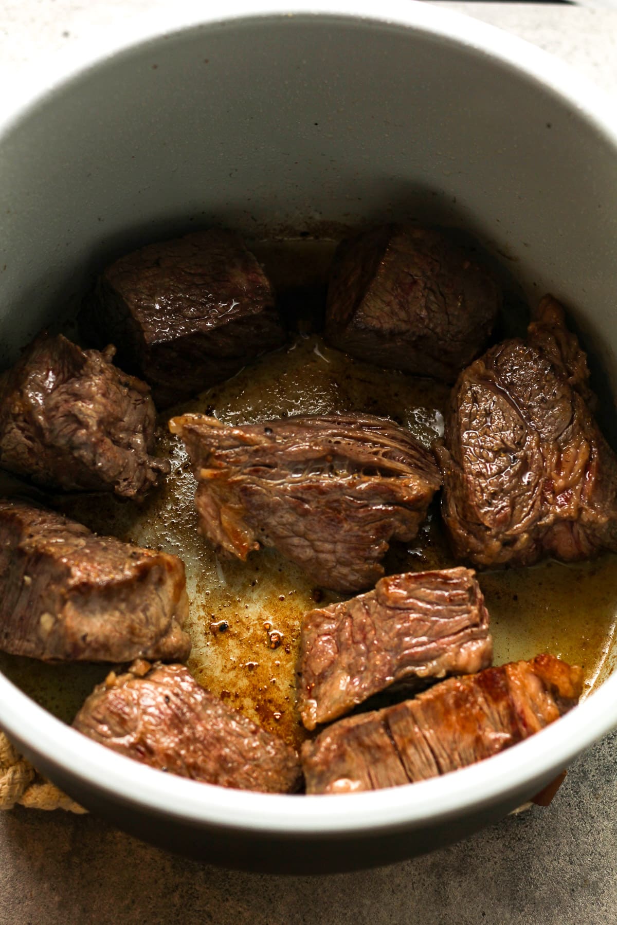 An instant pot of the seared beef chunks.