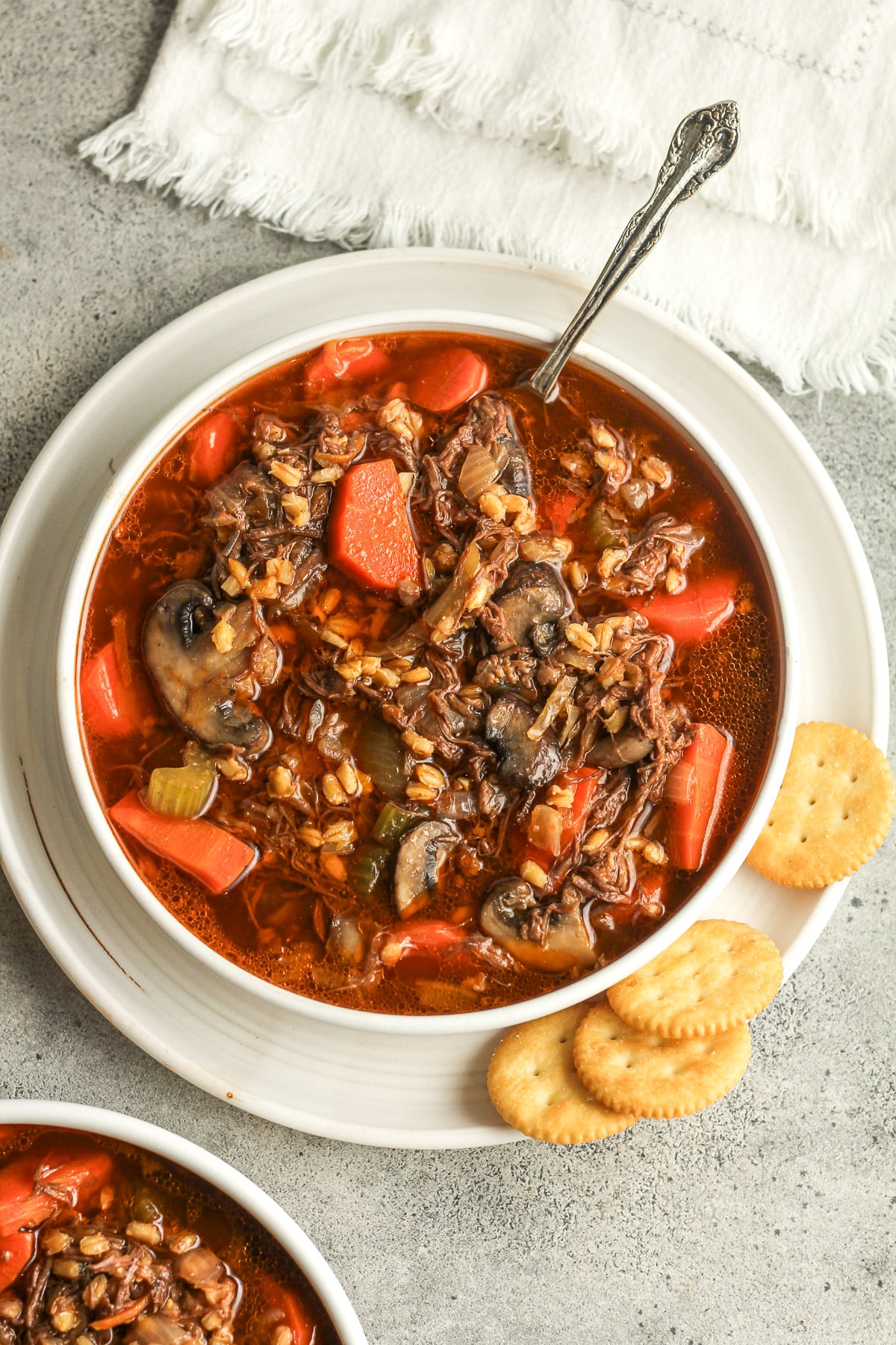 Overhead view of two bowls of beef barley soup with mushrooms.