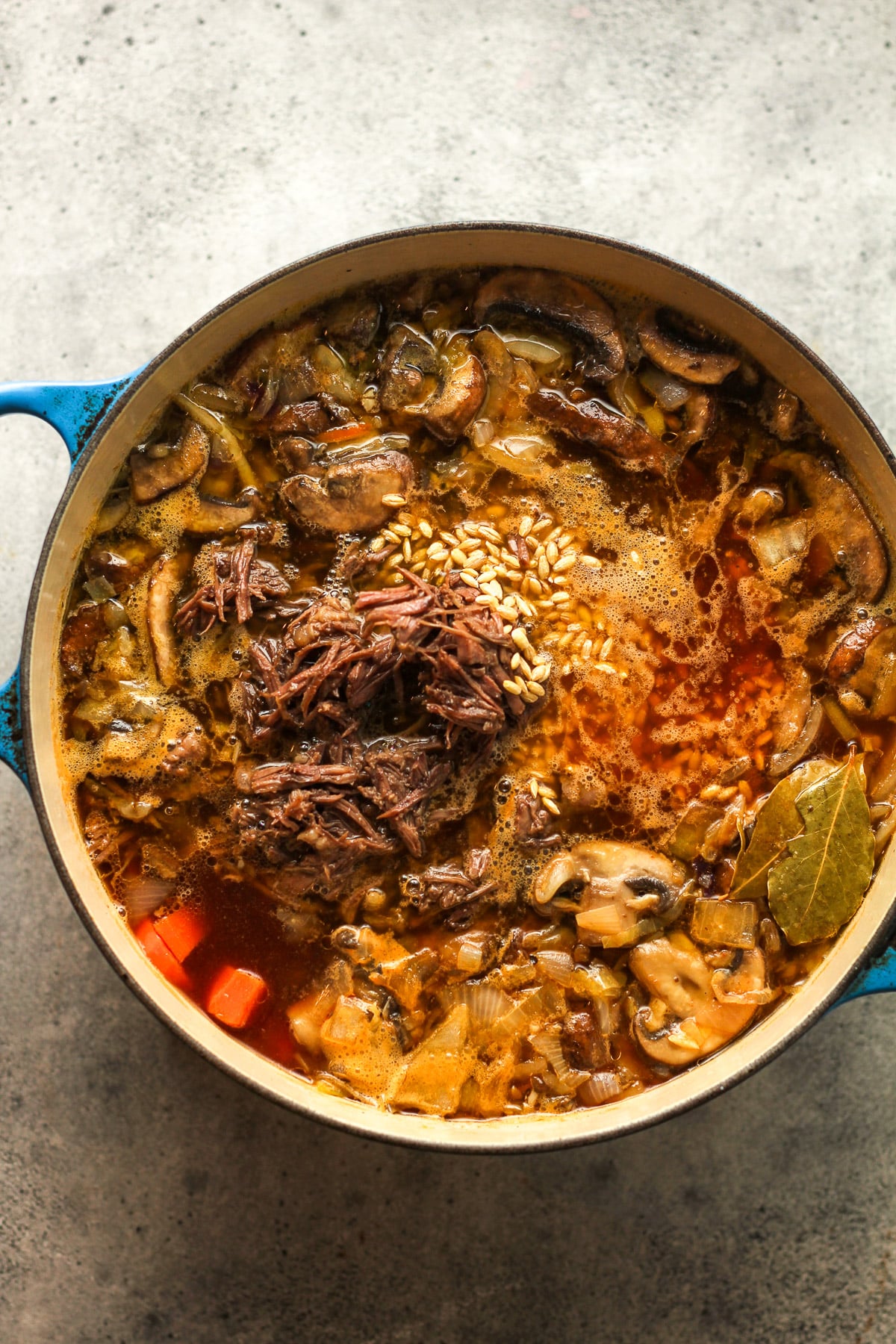 A pot of the beef soup after adding the shredded roast and the barley.