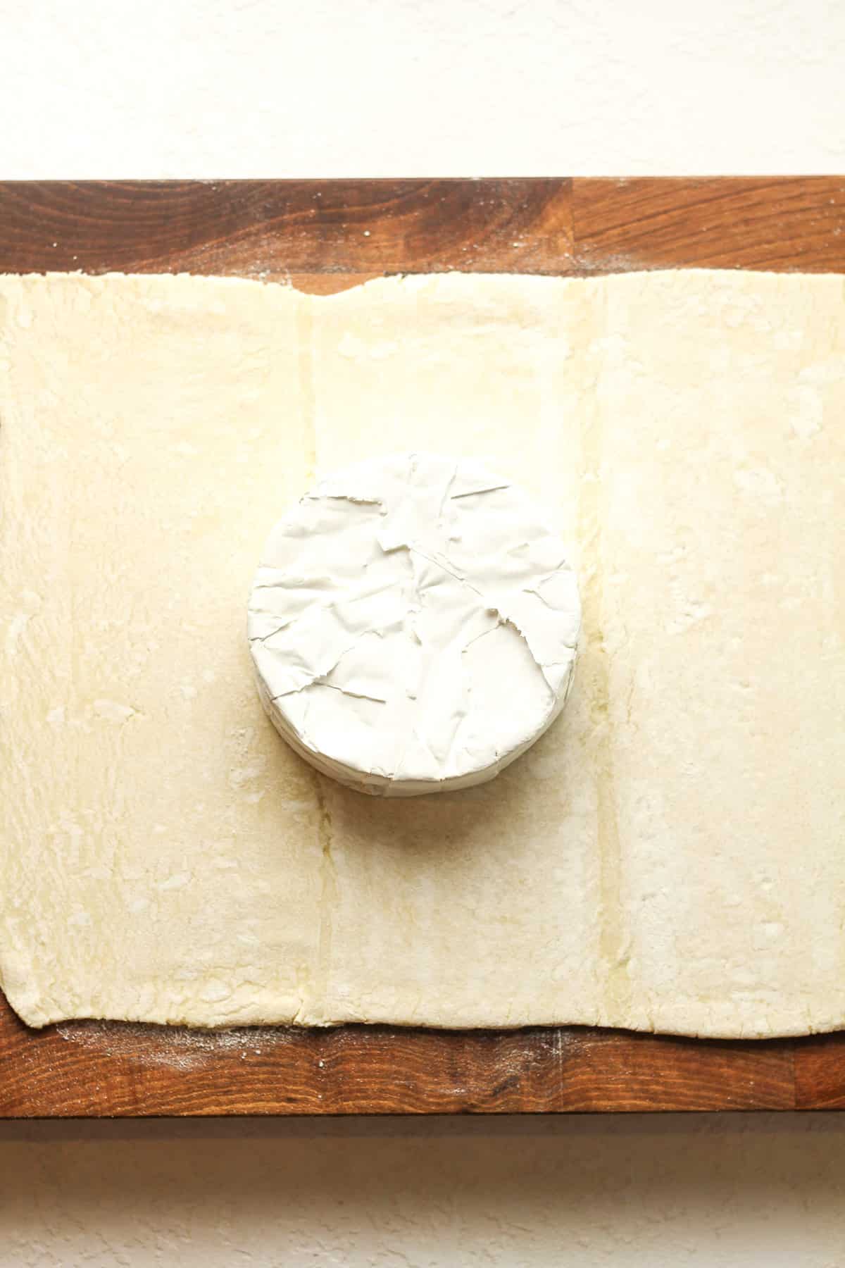 A sheet of puff pastry topped with a round of brie cheese.