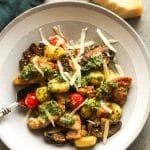 A bowl of chicken pesto gnocchi with shaved parmesan cheese.