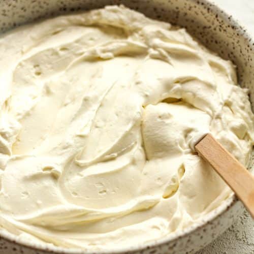 Side view of a bowl of the cream cheese filling with a spatula.