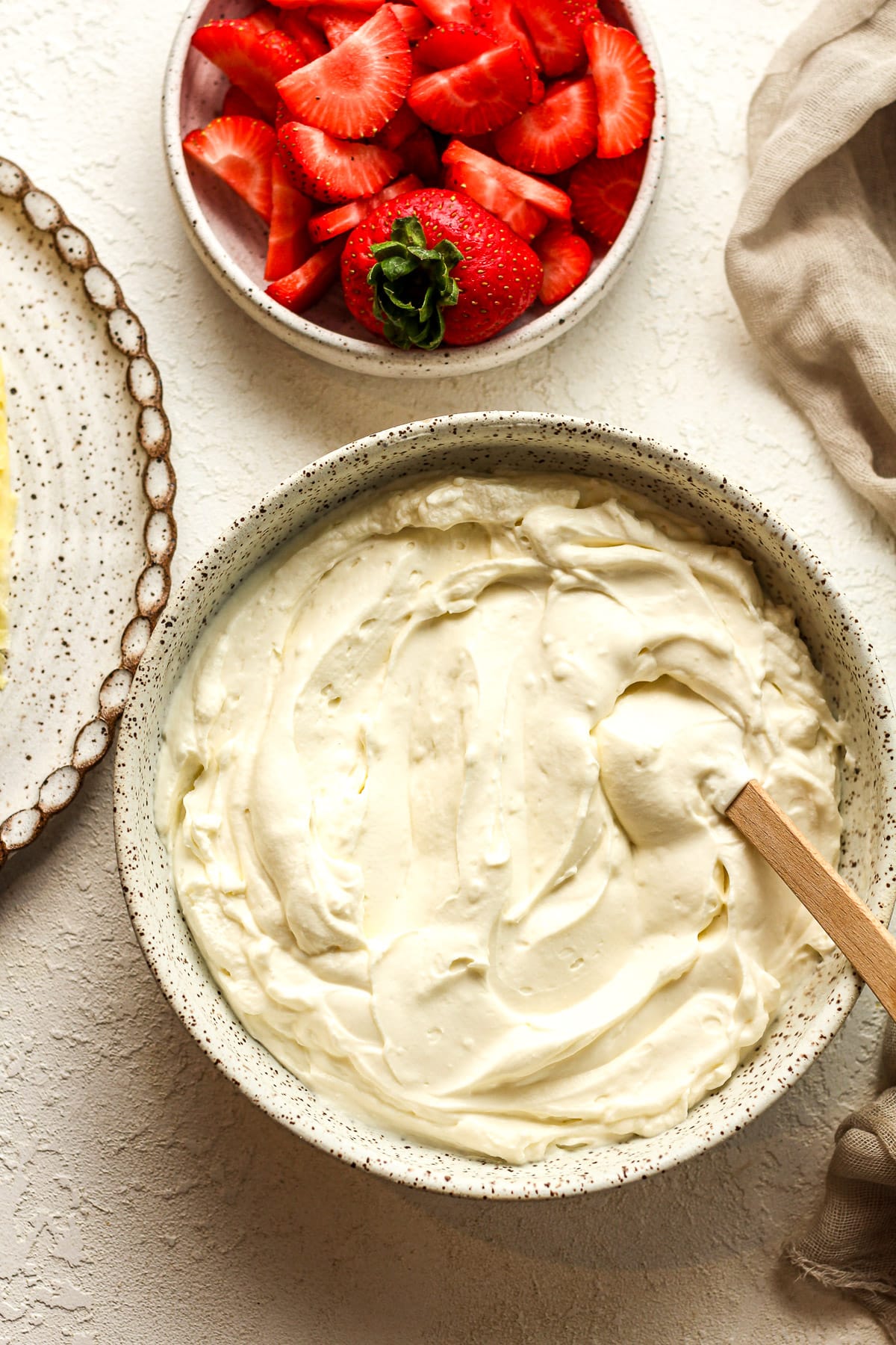 A bowl of the cream cheese filling next to a bowl of sliced strawberries.