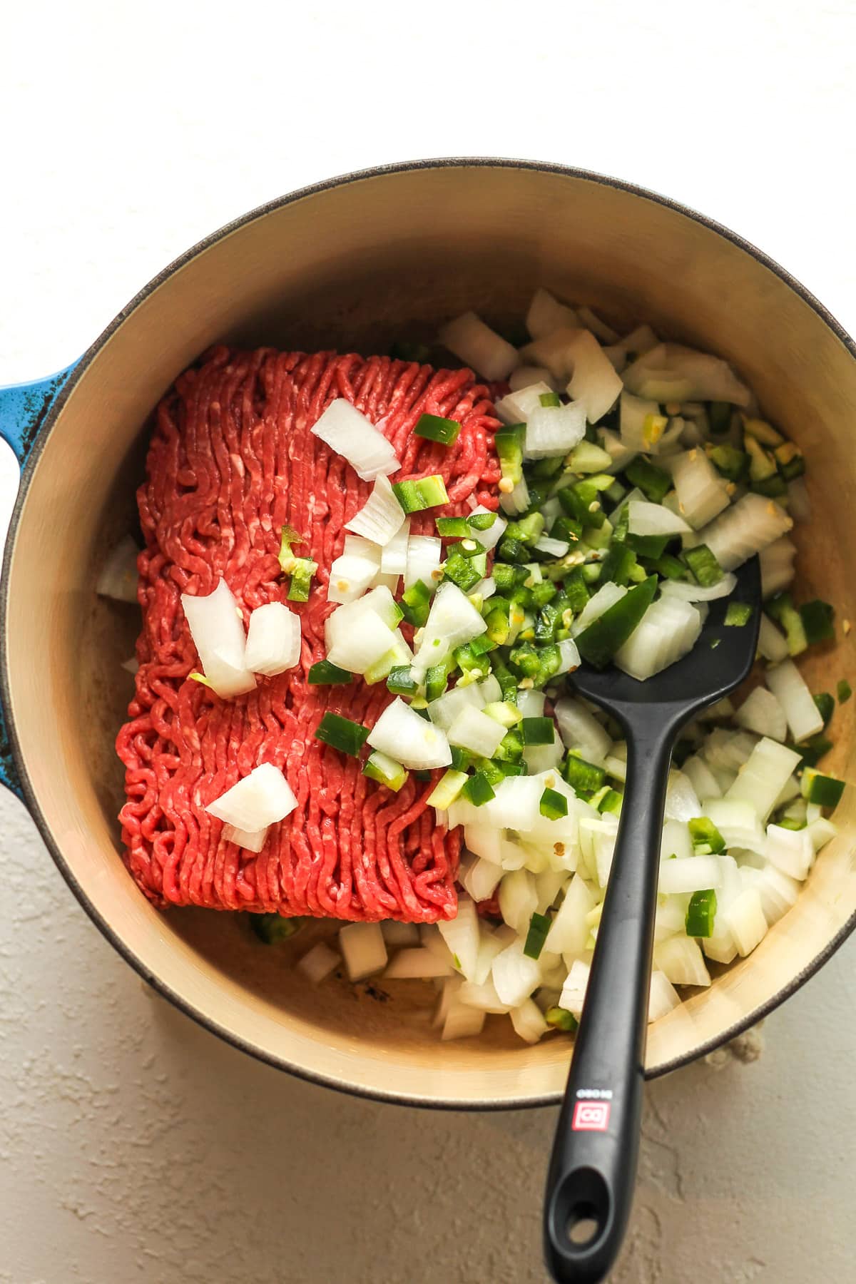 A stock pot of the raw beef plus the chopped onions and jalapeños.