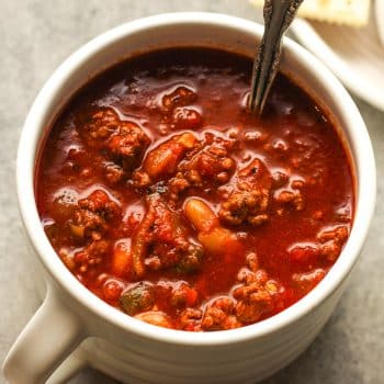 A mug of easy slow cooker chili with a spoon inside.