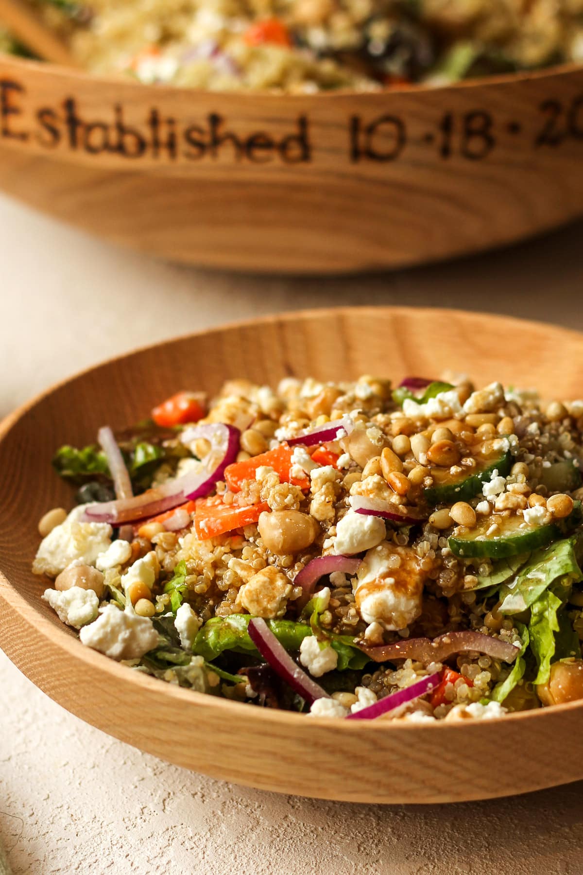 Closeup view of a small wooden bowl of quinoa salad with veggies and quinoa.