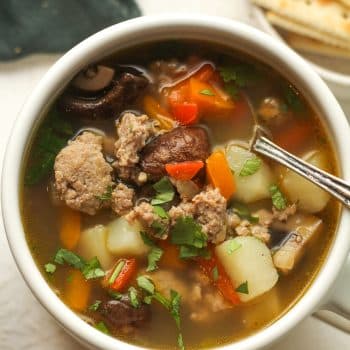 Overhead view of a mug of sausage vegetable soup.