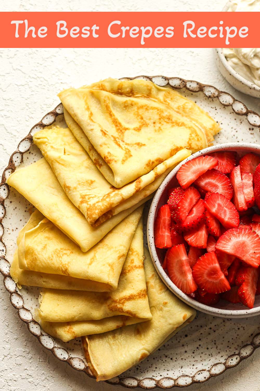 A plate of folded crepes with bowls of cream cheese filling and sliced strawberries.