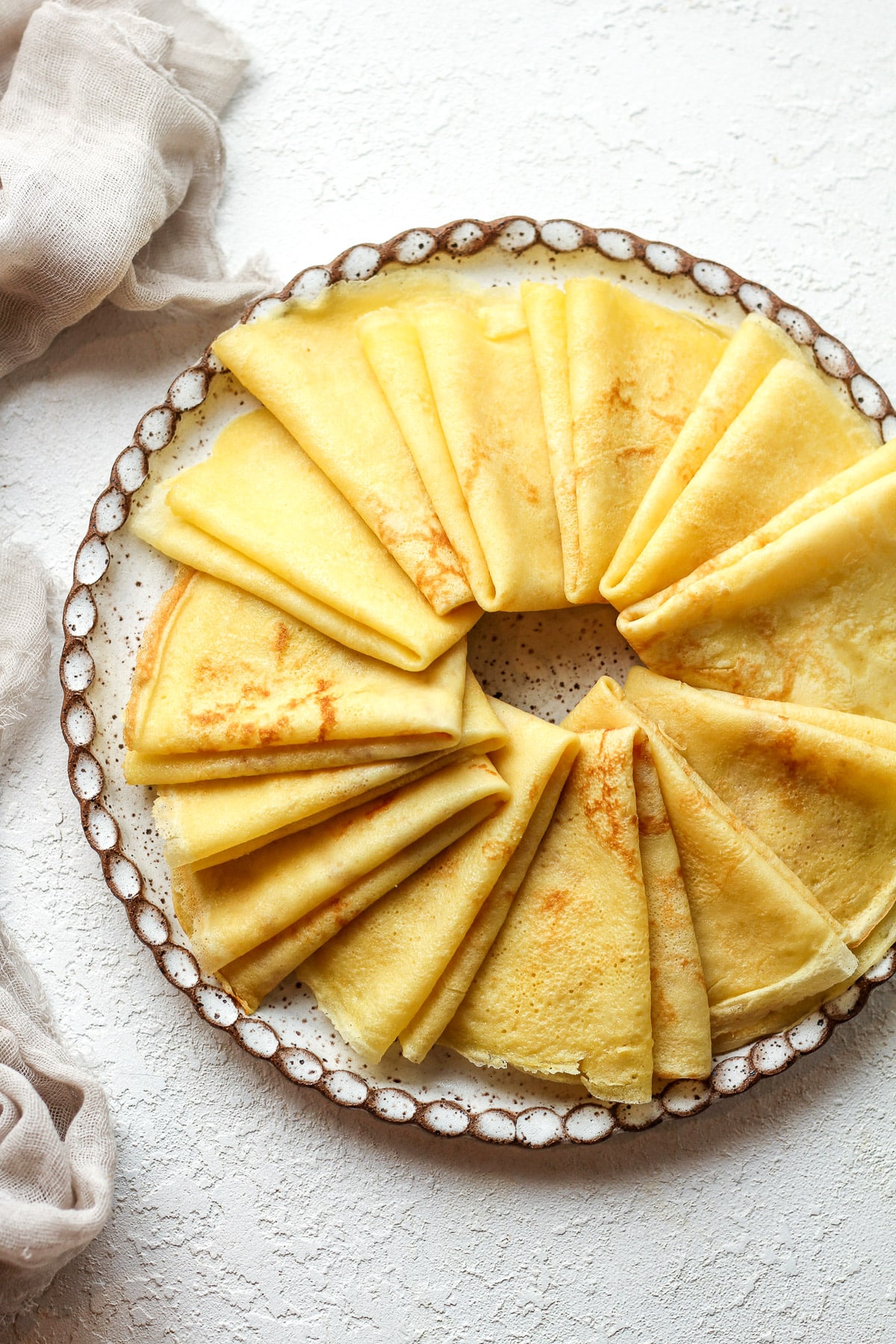 Overhead view of a plate of folded thin crepes.