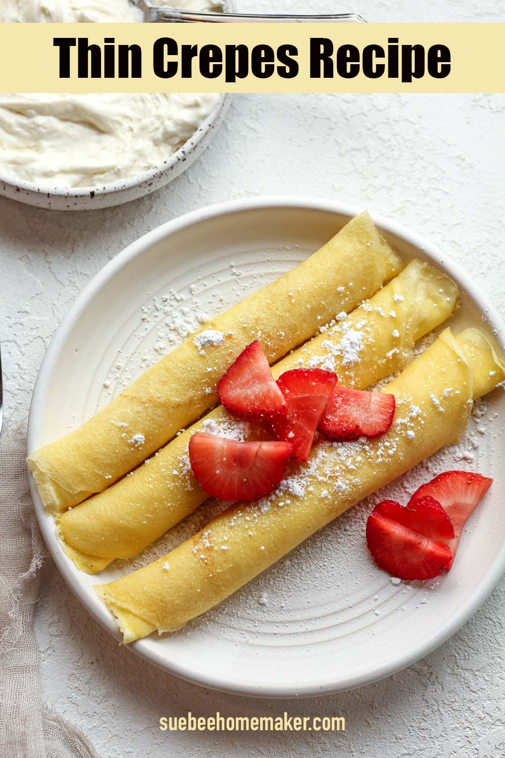 A plate of three rolled crepes filled with cream cheese filling and topped with sliced strawberries.