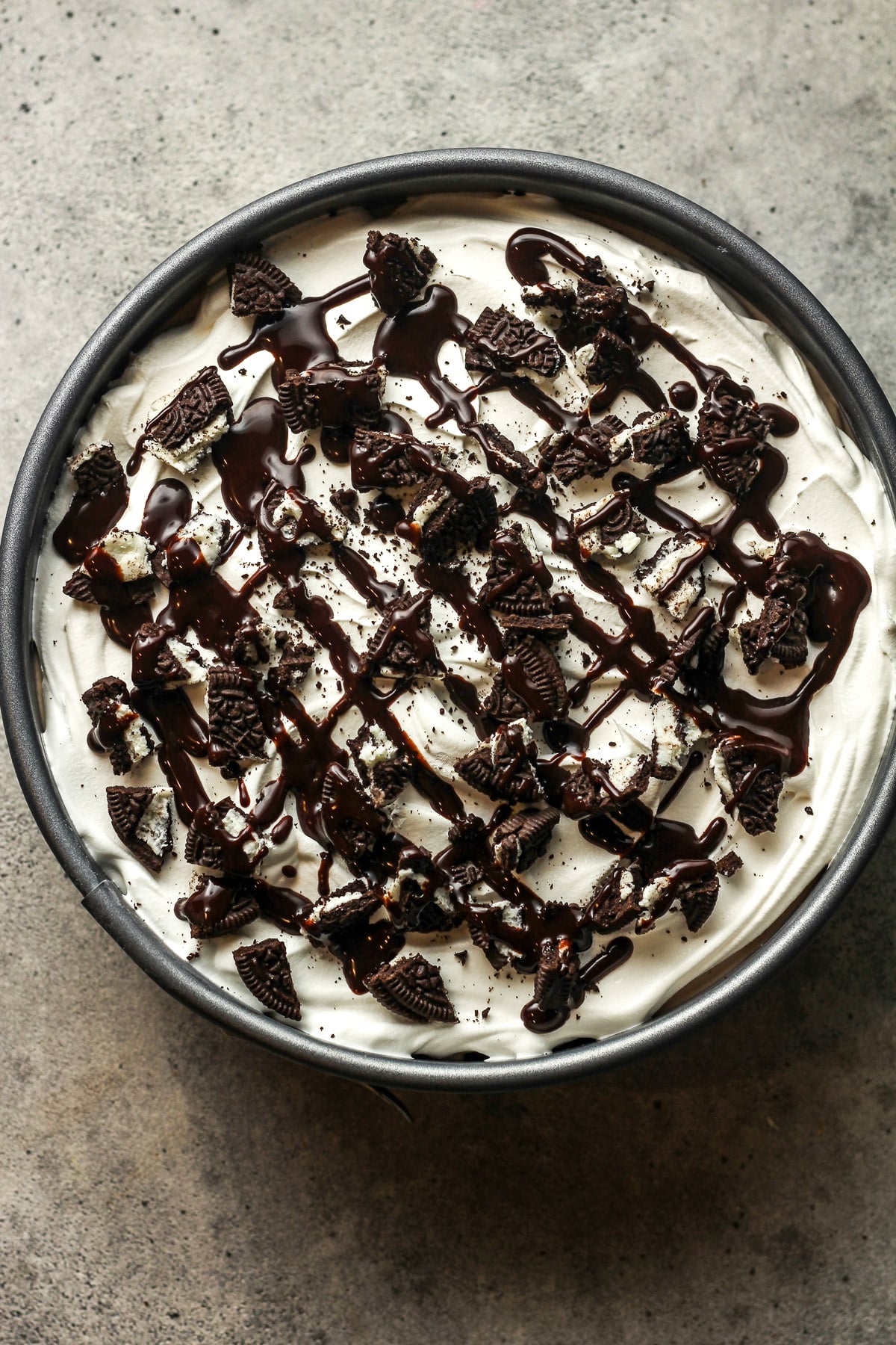 The finished Oreo ice cream pie with chocolate swirl and small pieces of Oreos on top.