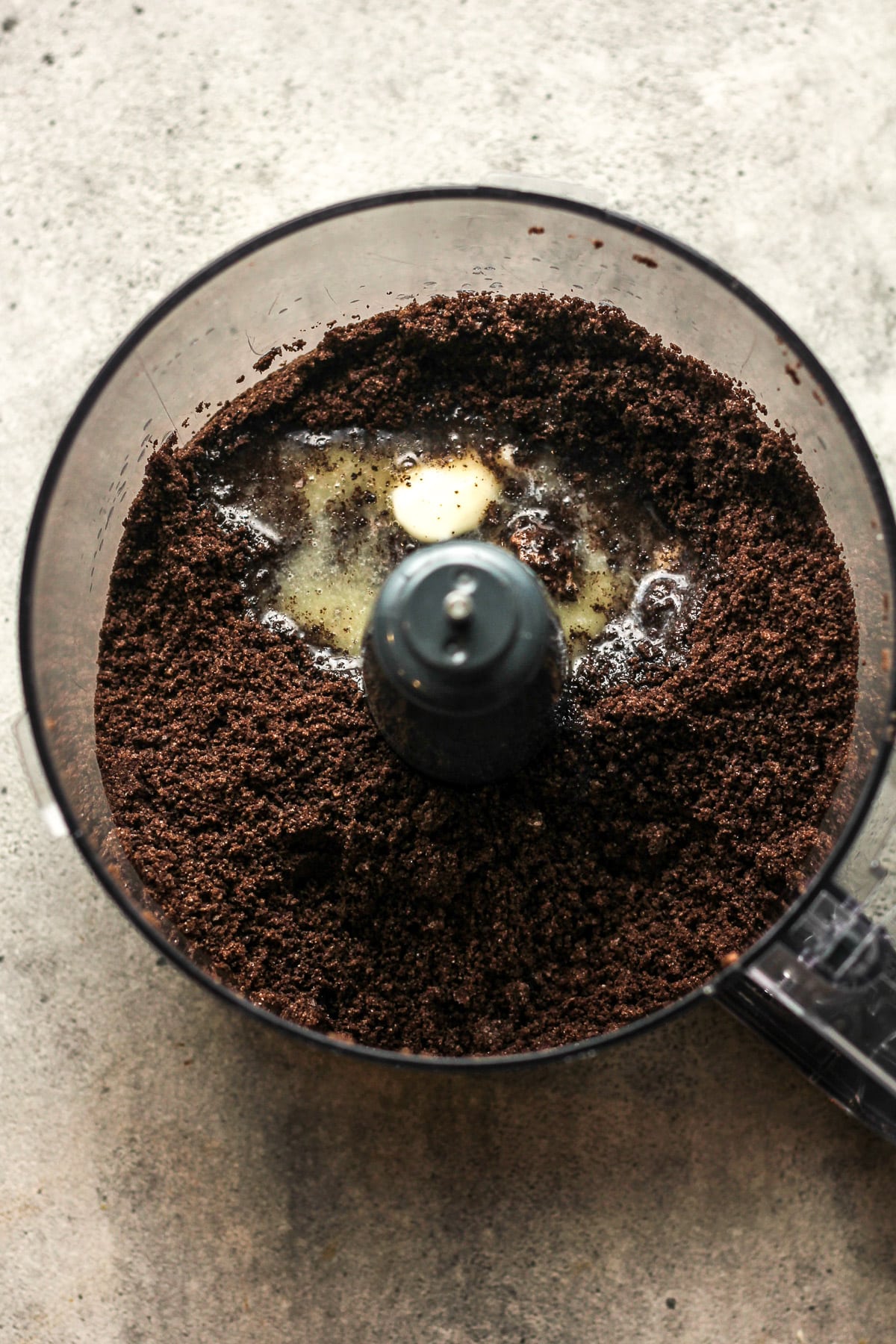 A food processor of the Oreo crumbs with melted butter on top.