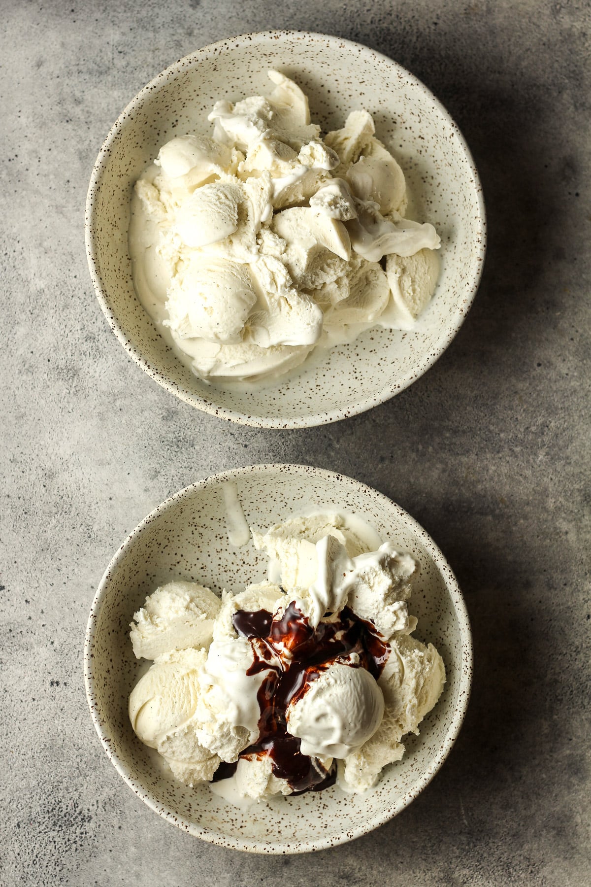 Two bowls - one with vanilla ice cream and another with vanilla plus chocolate syrup.