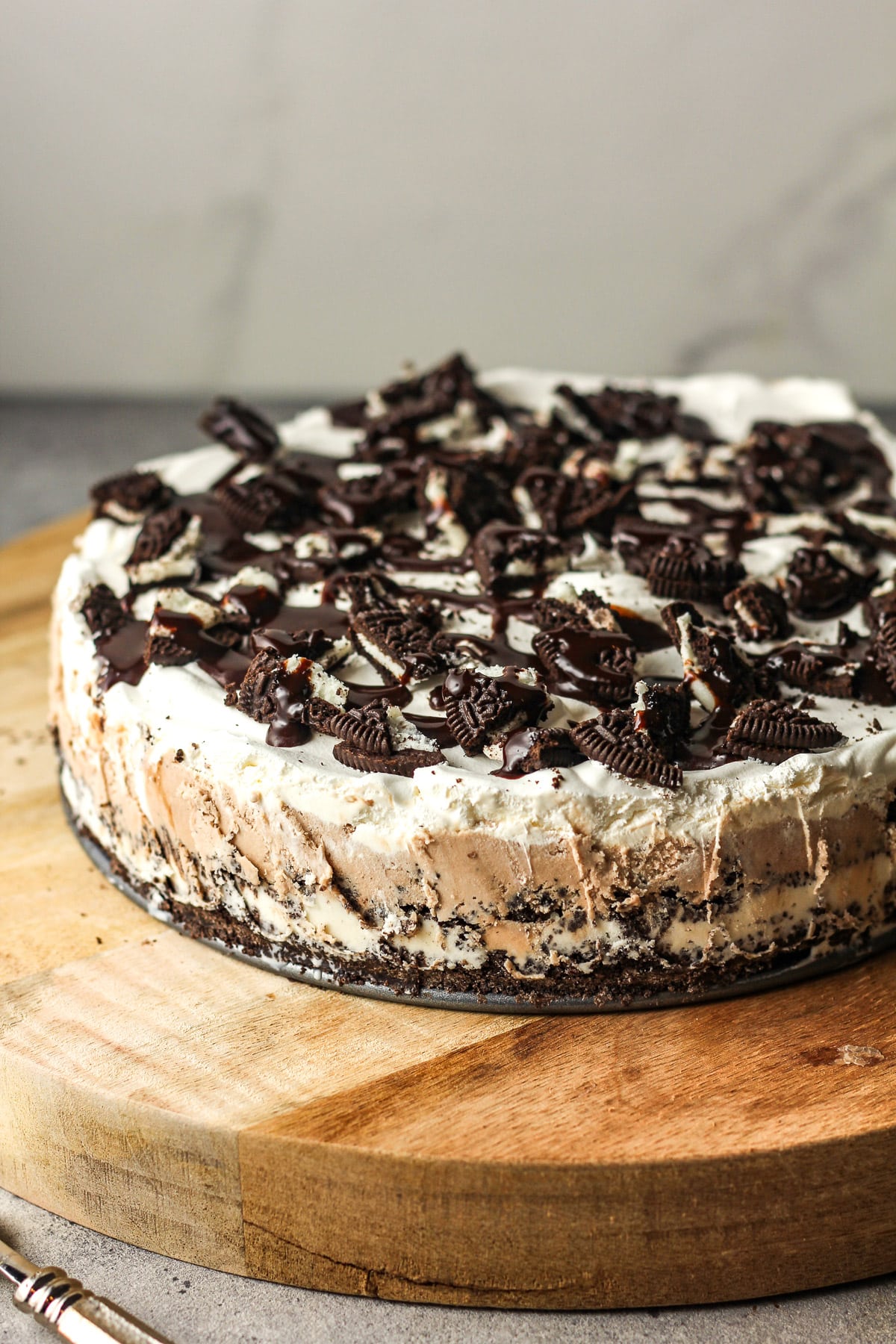 Side view of a whole Oreo ice cream pie on a round board.