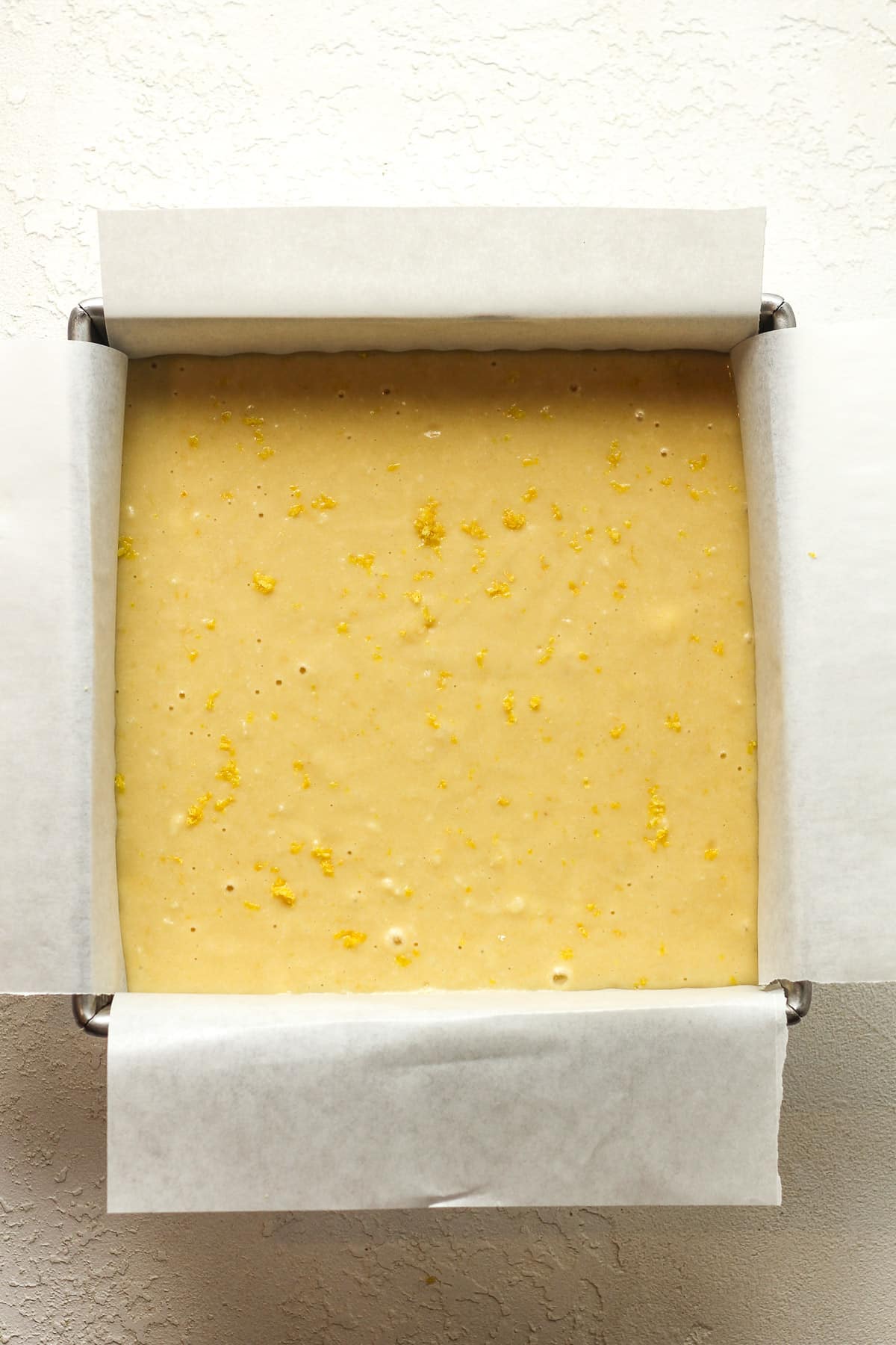 A square pan with the lemon cake batter.