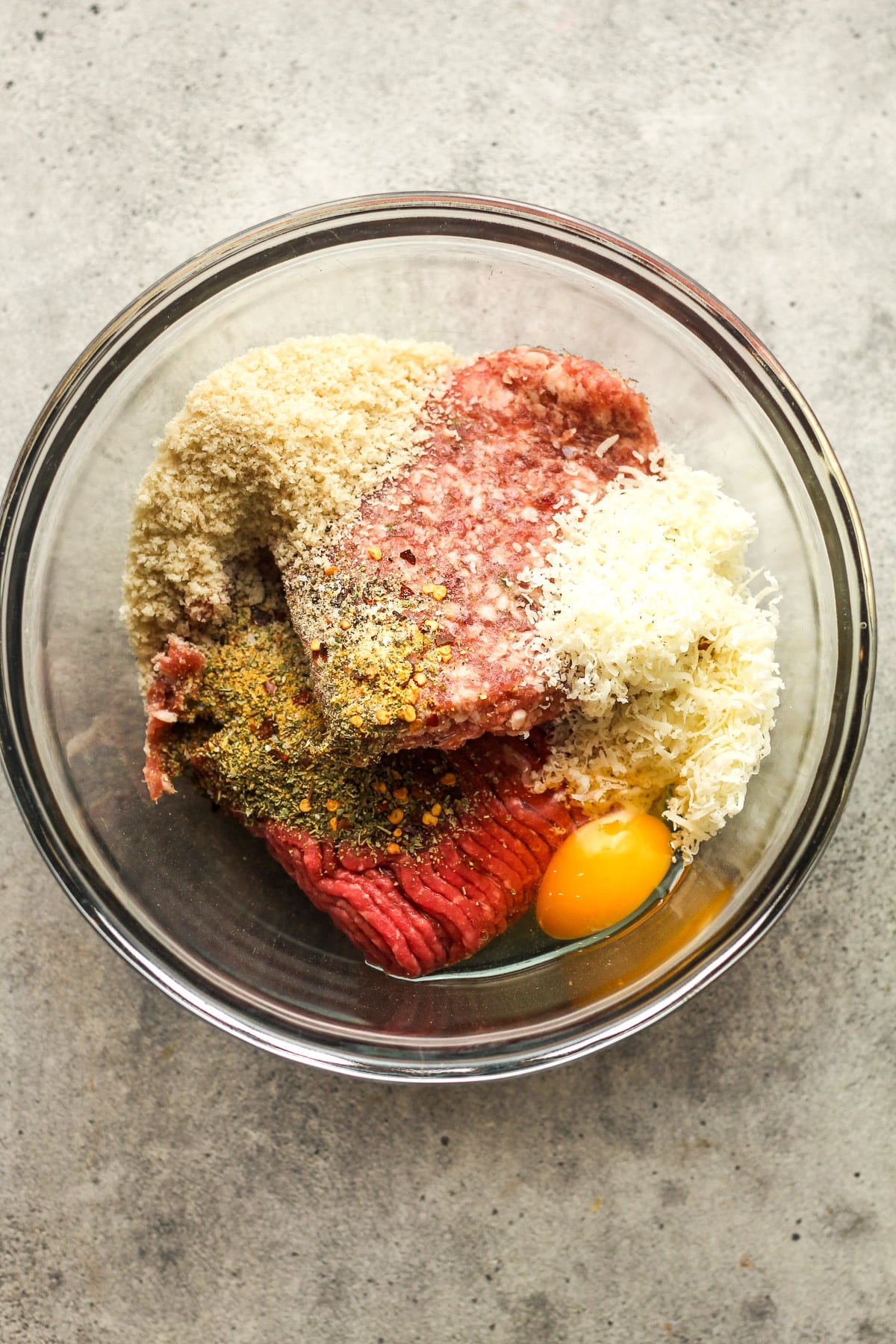 A bowl of the meatball ingredients separated by ingredient.