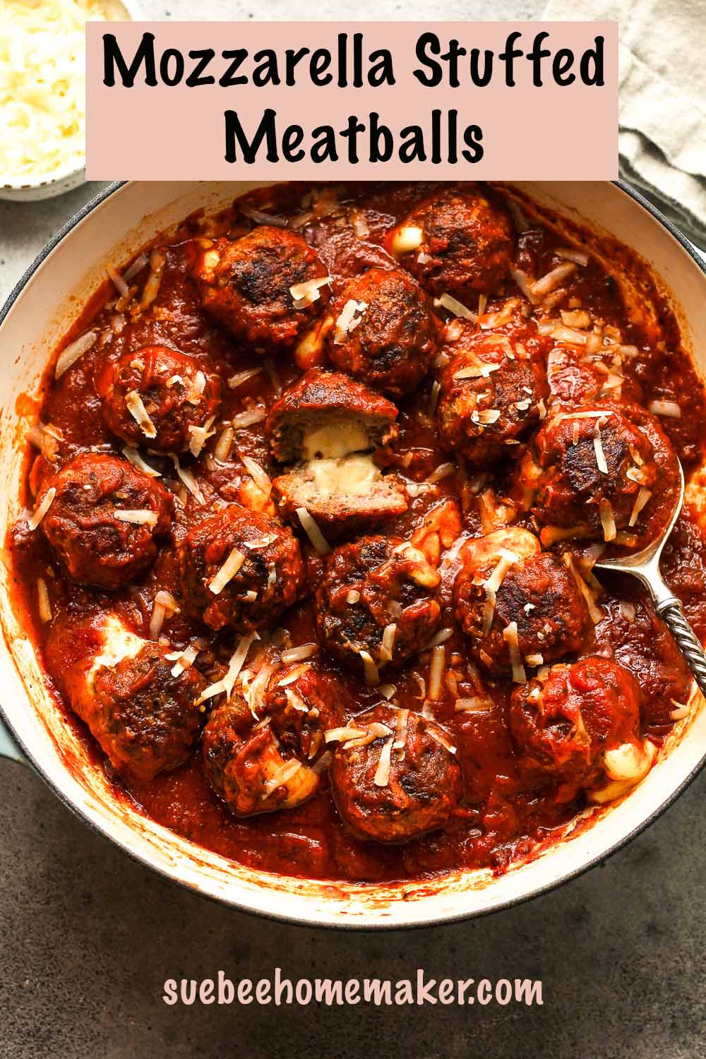 A pan of mozzarella stuffed meatballs and sauce, showing the insides of one of them.